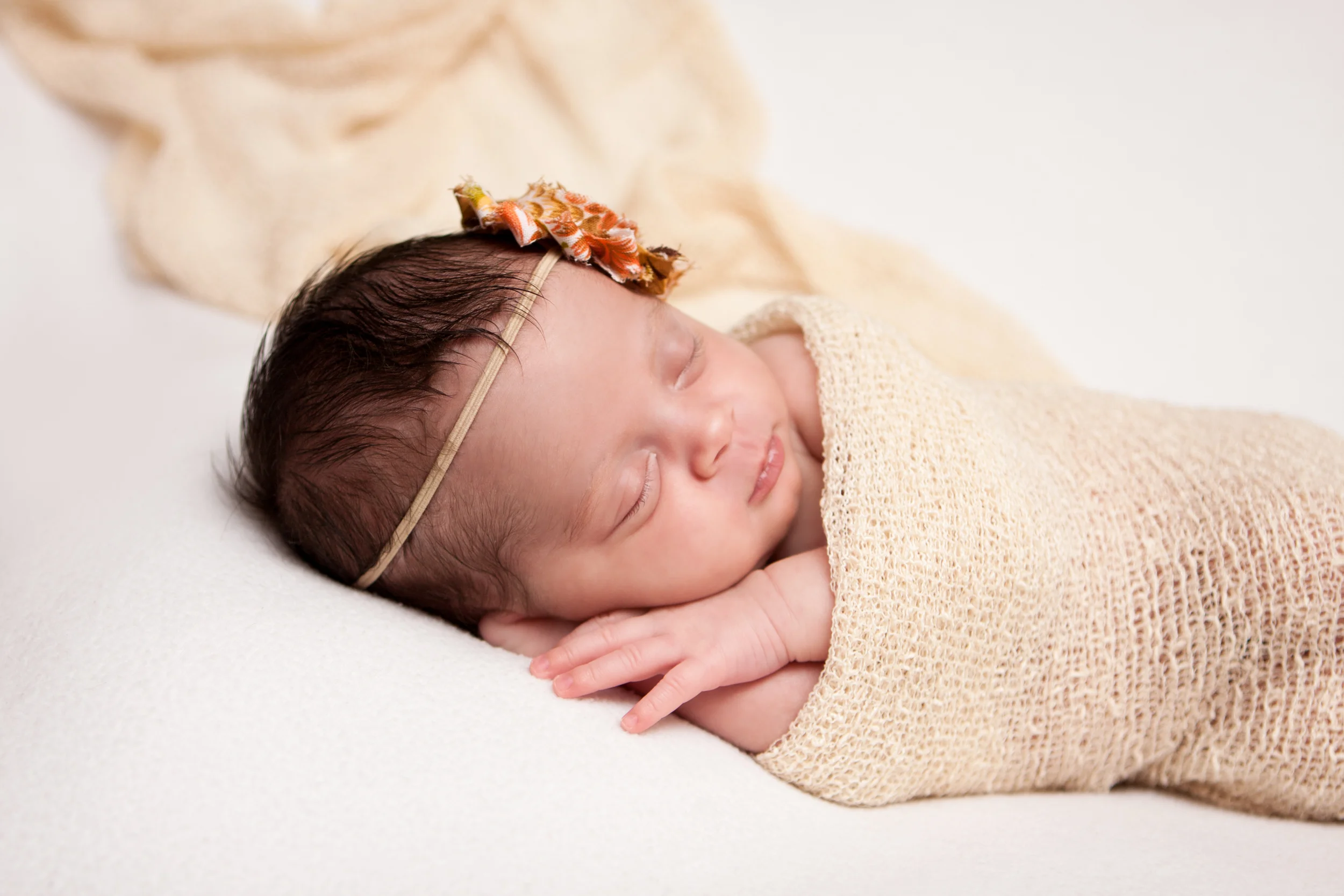 Newborn baby girl, shabby chic headband orange brown creme, creme white backdrop fabric blanket, creme tan stretch wrap, sleeping baby pose on beanbag, Westchester County, New Rochelle, White Plains, Pelham, New York Newborn Photographer, Amanda Noelle Photography