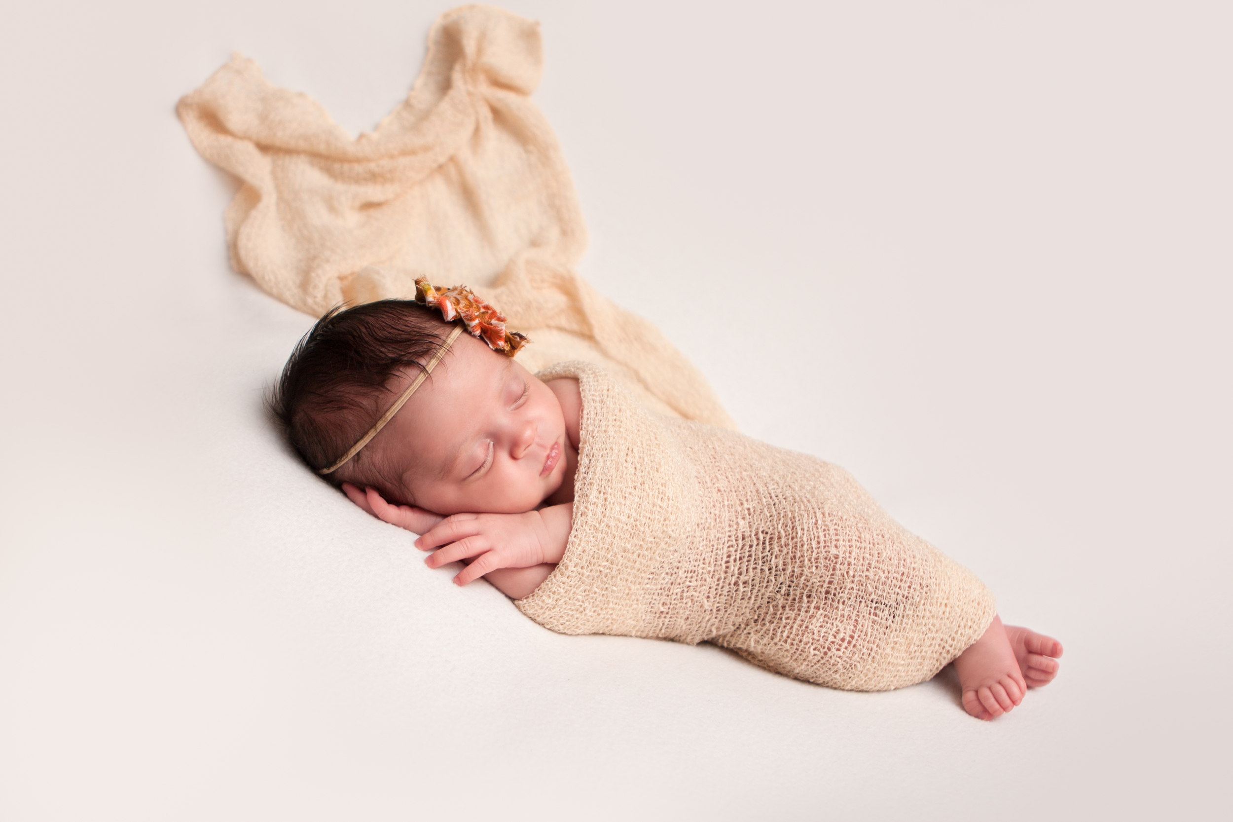 Newborn baby girl, shabby chic headband orange brown creme, creme white backdrop fabric blanket, creme tan stretch wrap, sleeping baby pose on beanbag, Westchester County, New Rochelle, White Plains, Pelham, New York Newborn Photographer, Amanda Noelle Photography