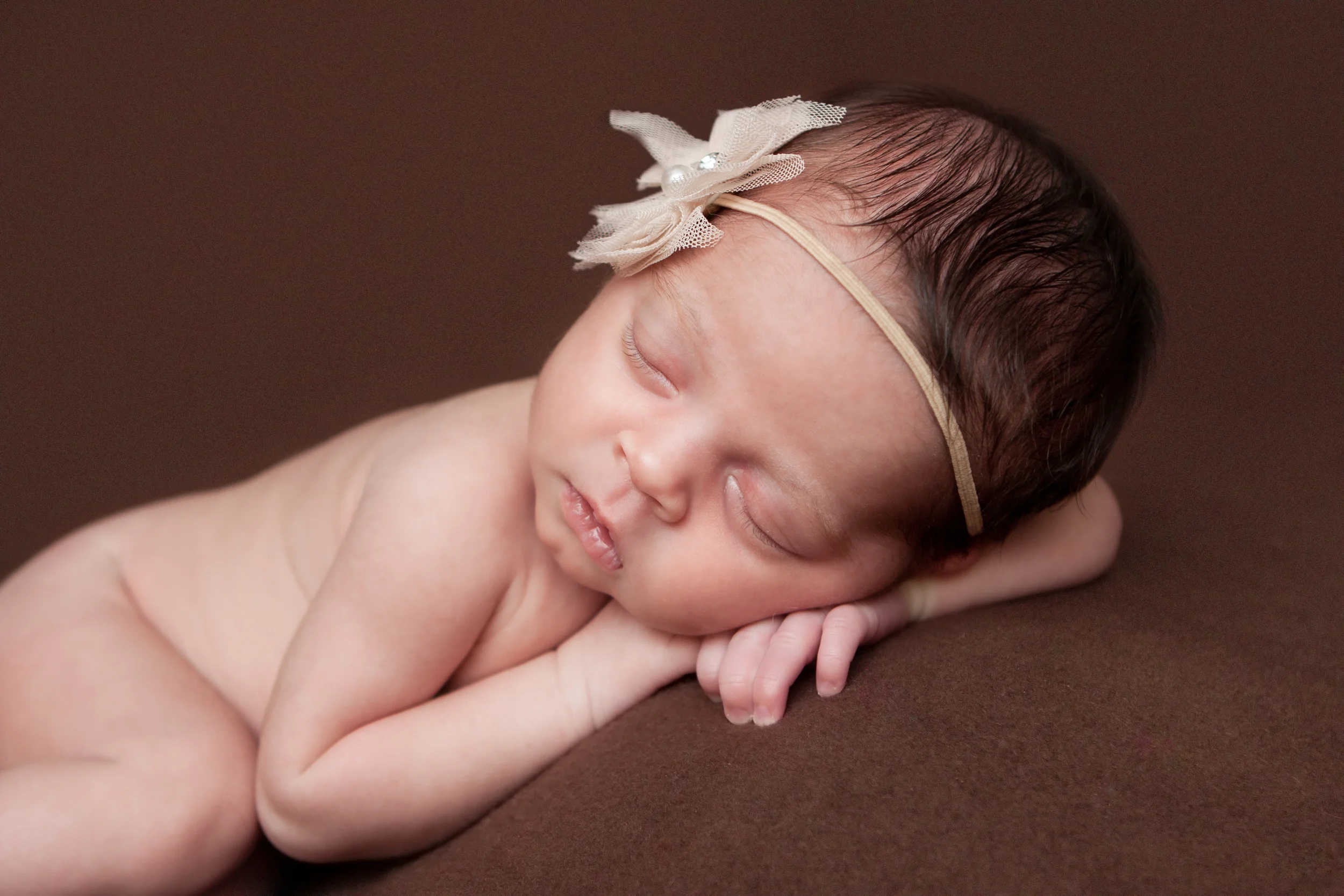 Newborn baby girl, flower headband creme nude pearl, brown backdrop fabric blanket, head on hands pose, sleeping baby pose on beanbag, Westchester County, New Rochelle, White Plains, Pelham, New York Newborn Photographer, Amanda Noelle Photography