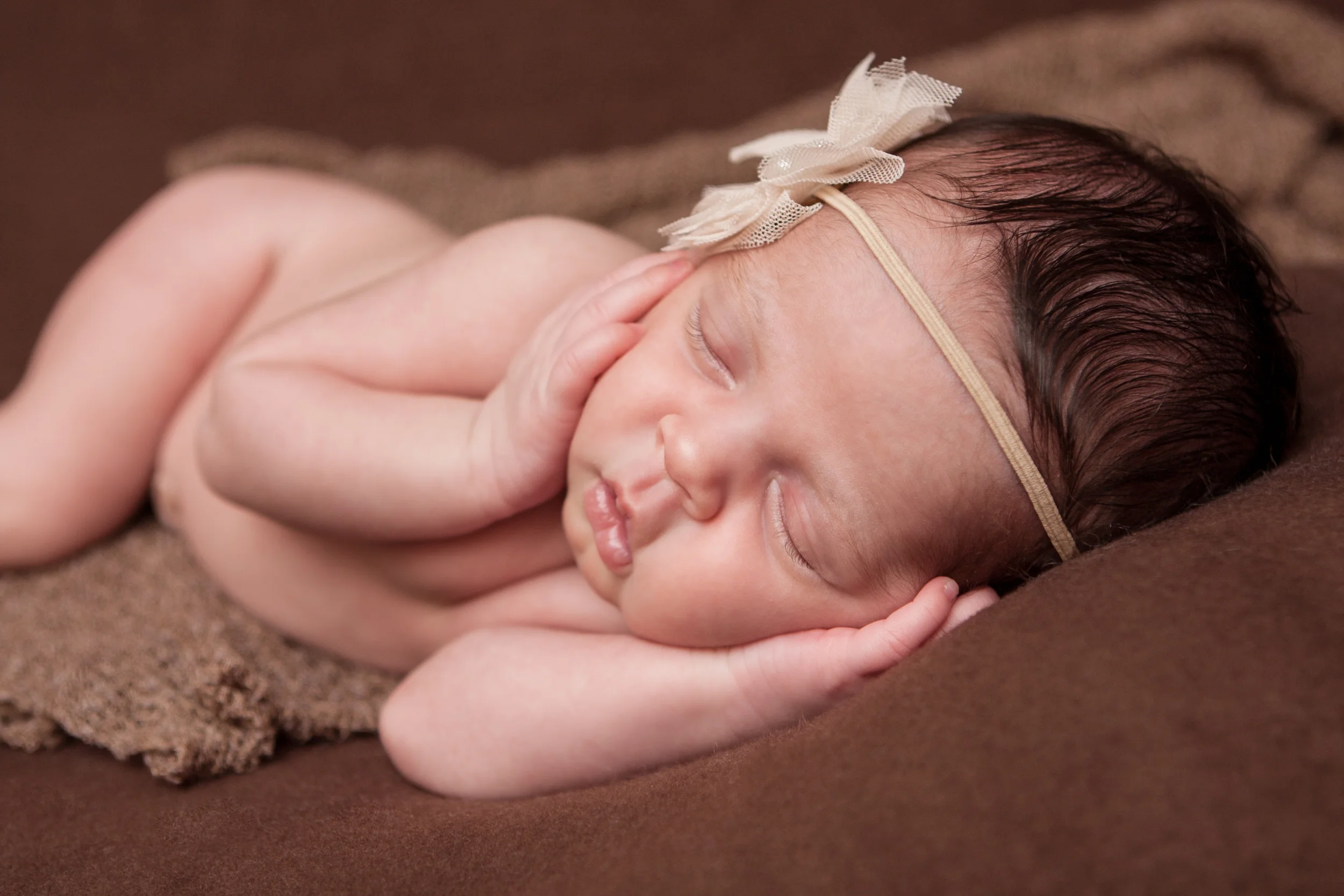 Newborn baby girl, nude creme tan pearl headband , brown backdrop fabric blanket, brown stretch wrap, head in hands on cheeks pose, sleeping baby pose on beanbag, Westchester County, New Rochelle, White Plains, Pelham, New York Newborn Photographer, Amanda Noelle Photography