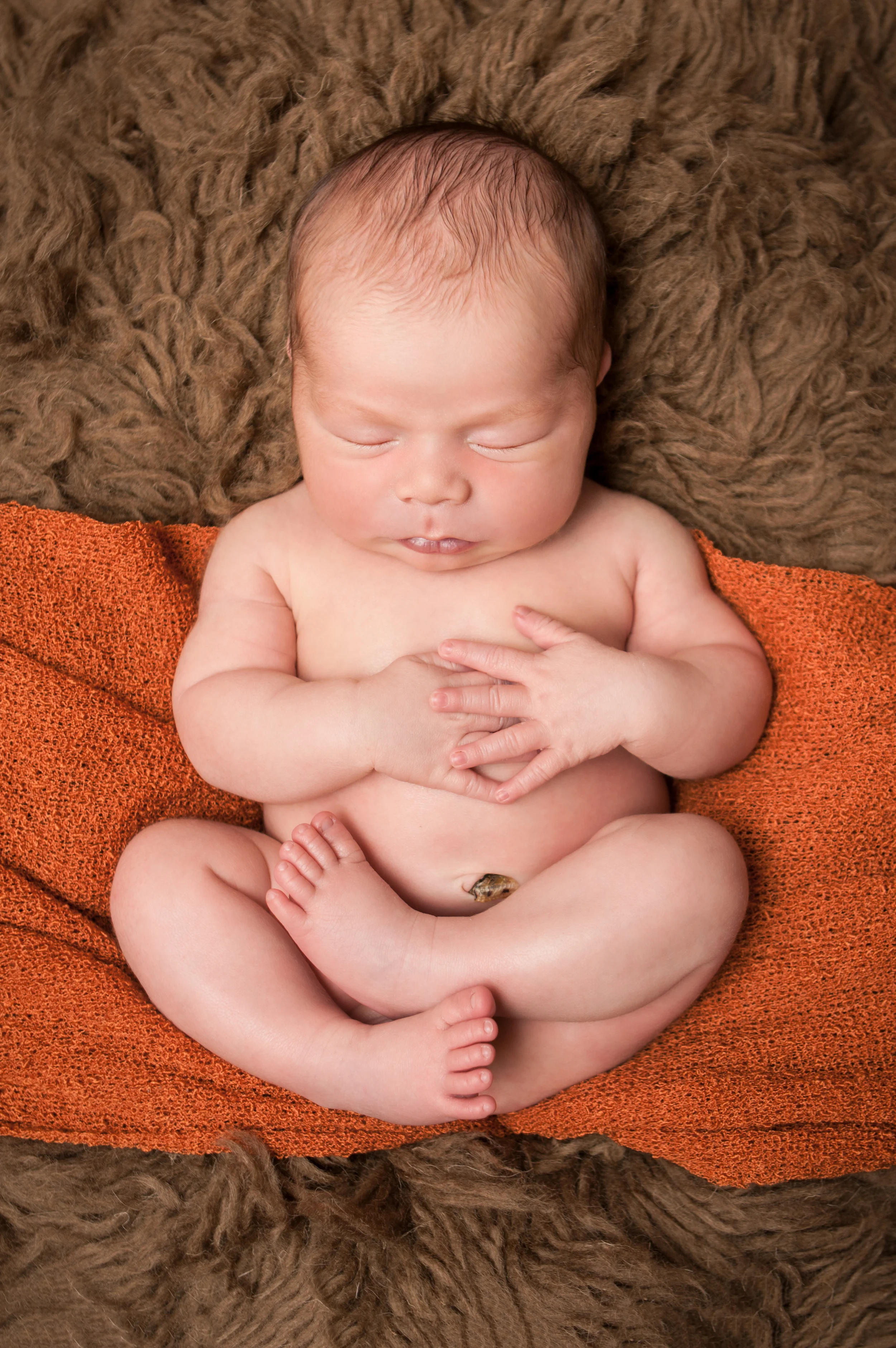 Newborn baby boy chubby, orange stretch knit wrap on brown flokati rug, Westchester County, New York newborn photographer, Amanda Noelle Photography.
