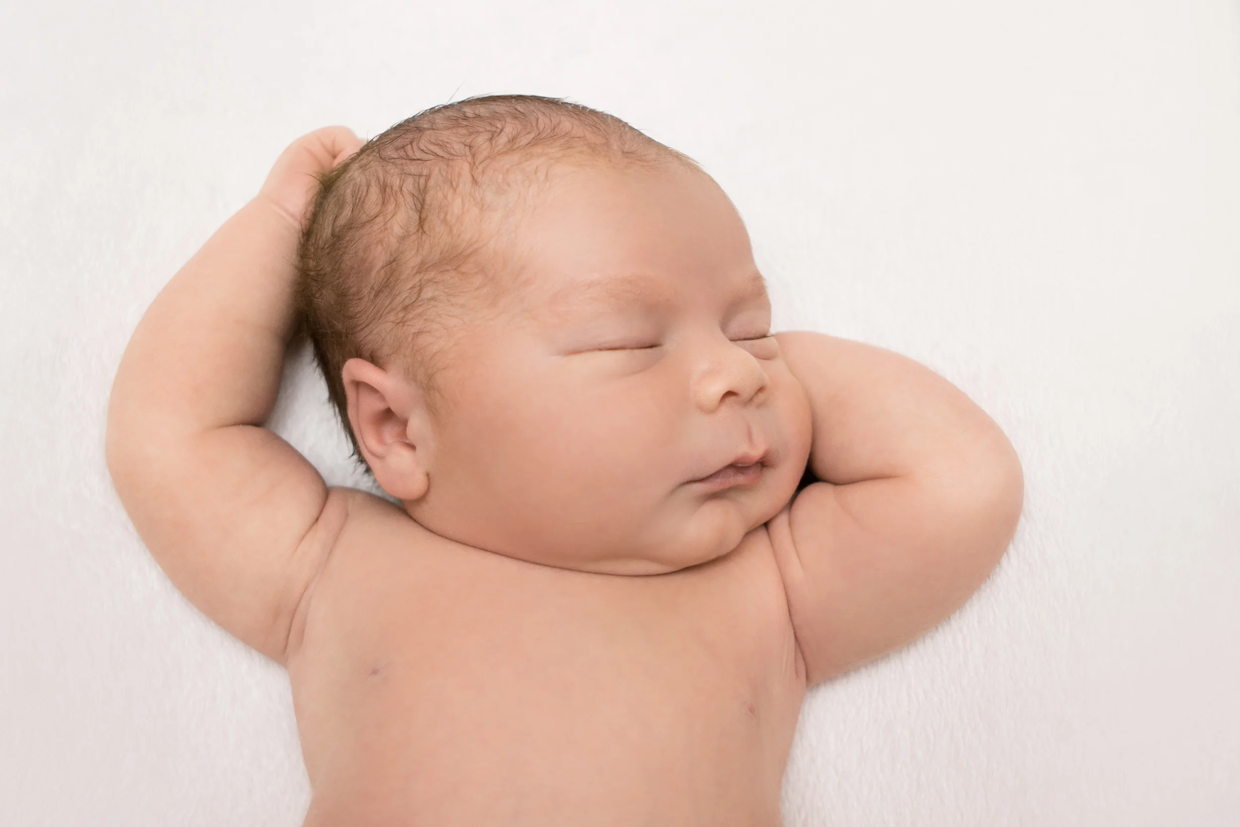 Newborn baby boy chubby, on cream creme white fabric blanket backdrop bean bag pose, Westchester County, New York newborn photographer, Amanda Noelle Photography.