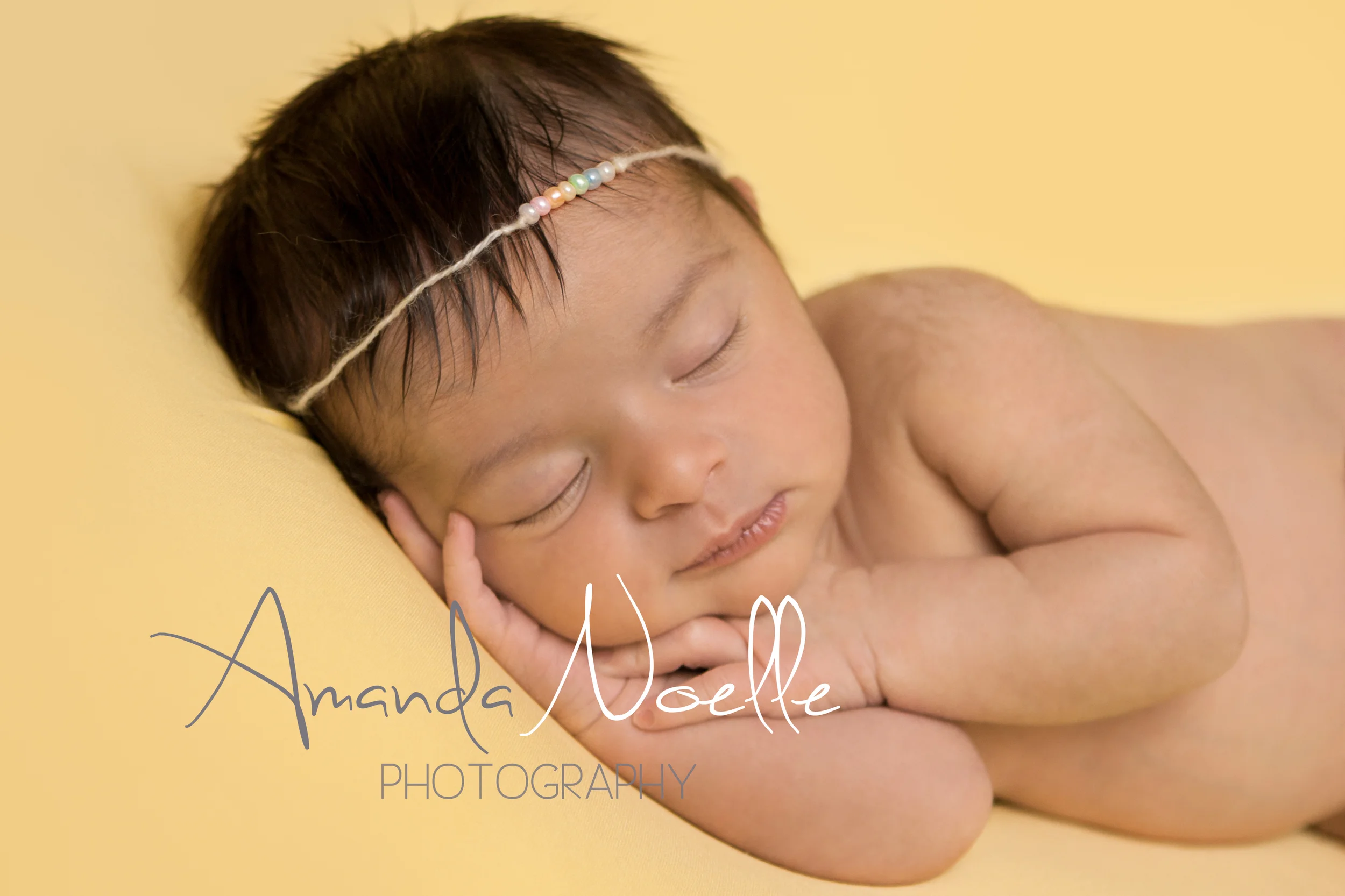 Newborn baby girl sleeping with rainbow bead tieback headband on yellow fabric backdrop, beanbag pose, Westchester, County New York Newborn Photographer, Amanda Noelle Photography.