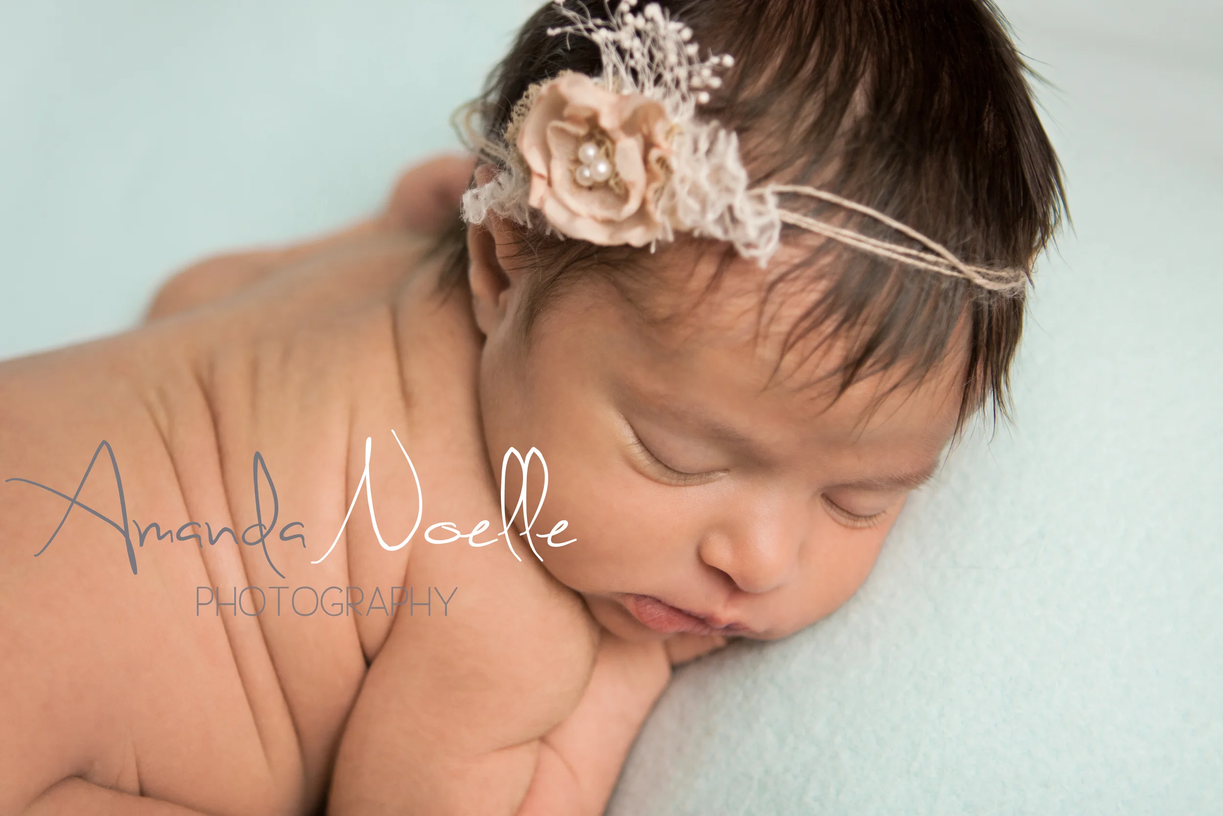 Newborn baby girl sleeping with shabby chic pink flower tieback headband on teal mint aqua fabric backdrop, tushy up beanbag pose, Westchester, County New York Newborn Photographer, Amanda Noelle Photography.
