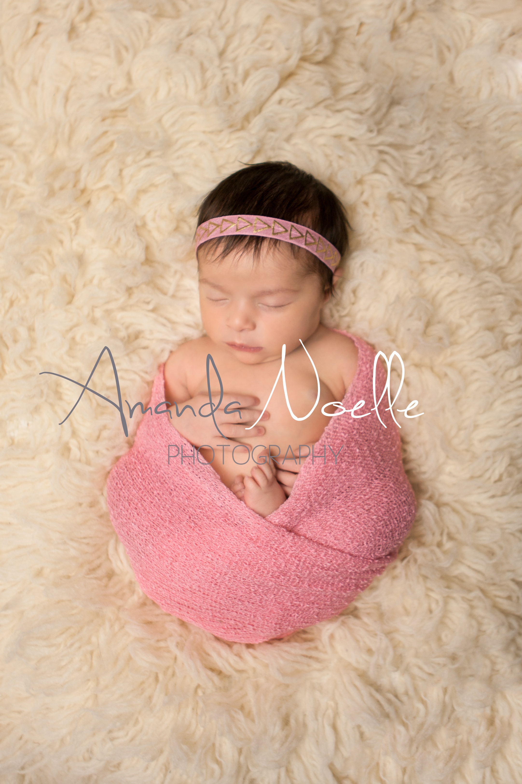Newborn baby girl sleeping with pink and gold headband wrapped in stretch knit pink wrap on cream creme flokati rug, Westchester, County New York Newborn Photographer, Amanda Noelle Photography.
