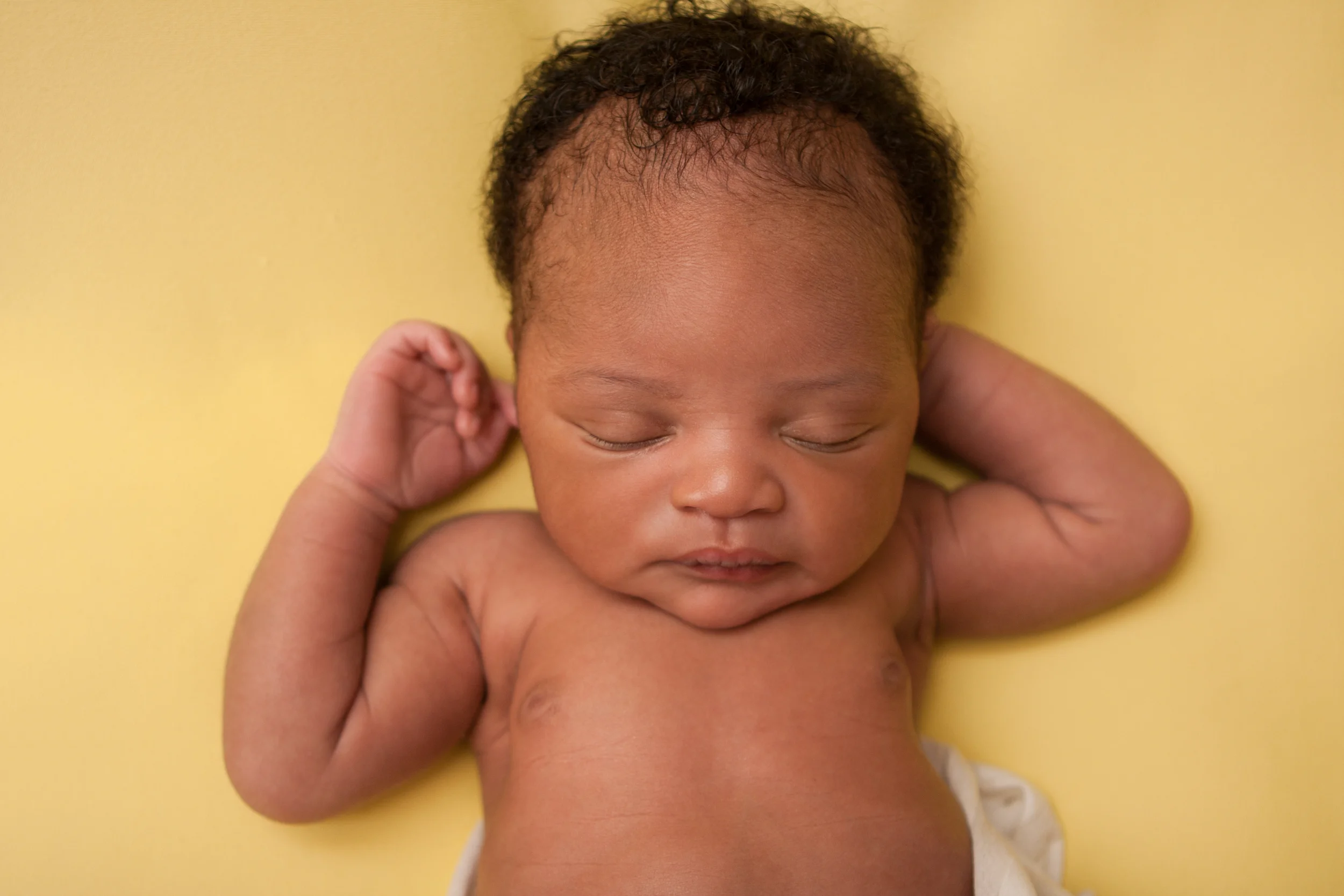 Newborn baby boy j black curly hair, african american, sleeping pose on yellow fabric blanket backdrop, Westchester County, New York Newborn Photographer, Amanda Noelle Photography.