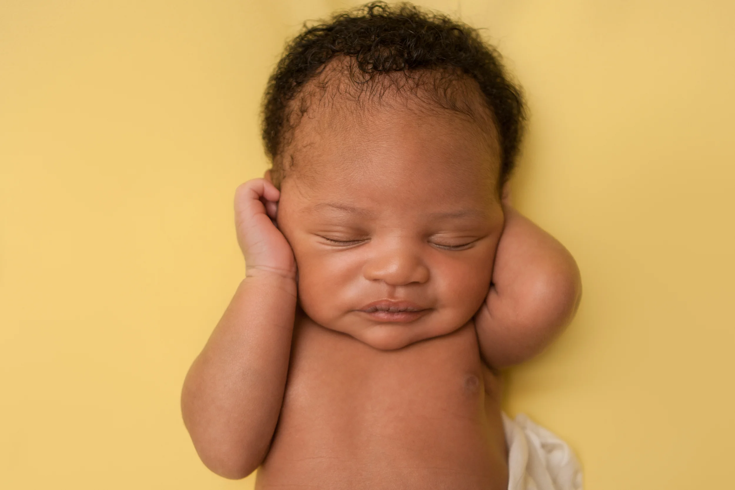 Newborn baby boy j black curly hair, african american, sleeping pose on yellow fabric blanket backdrop, Westchester County, New York Newborn Photographer, Amanda Noelle Photography.