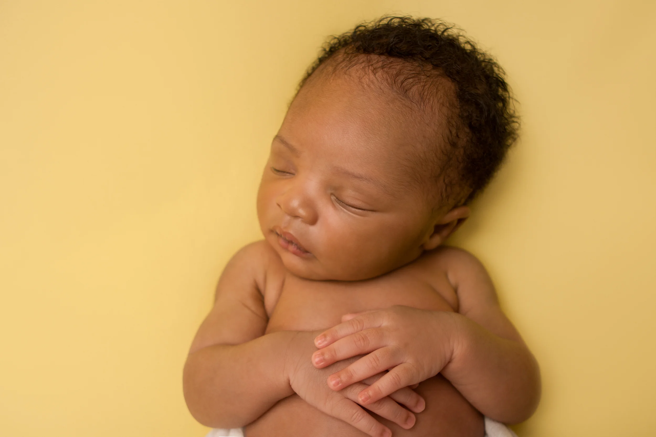 Newborn baby boy j black curly hair, african american, sleeping pose on yellow fabric blanket backdrop, Westchester County, New York Newborn Photographer, Amanda Noelle Photography.