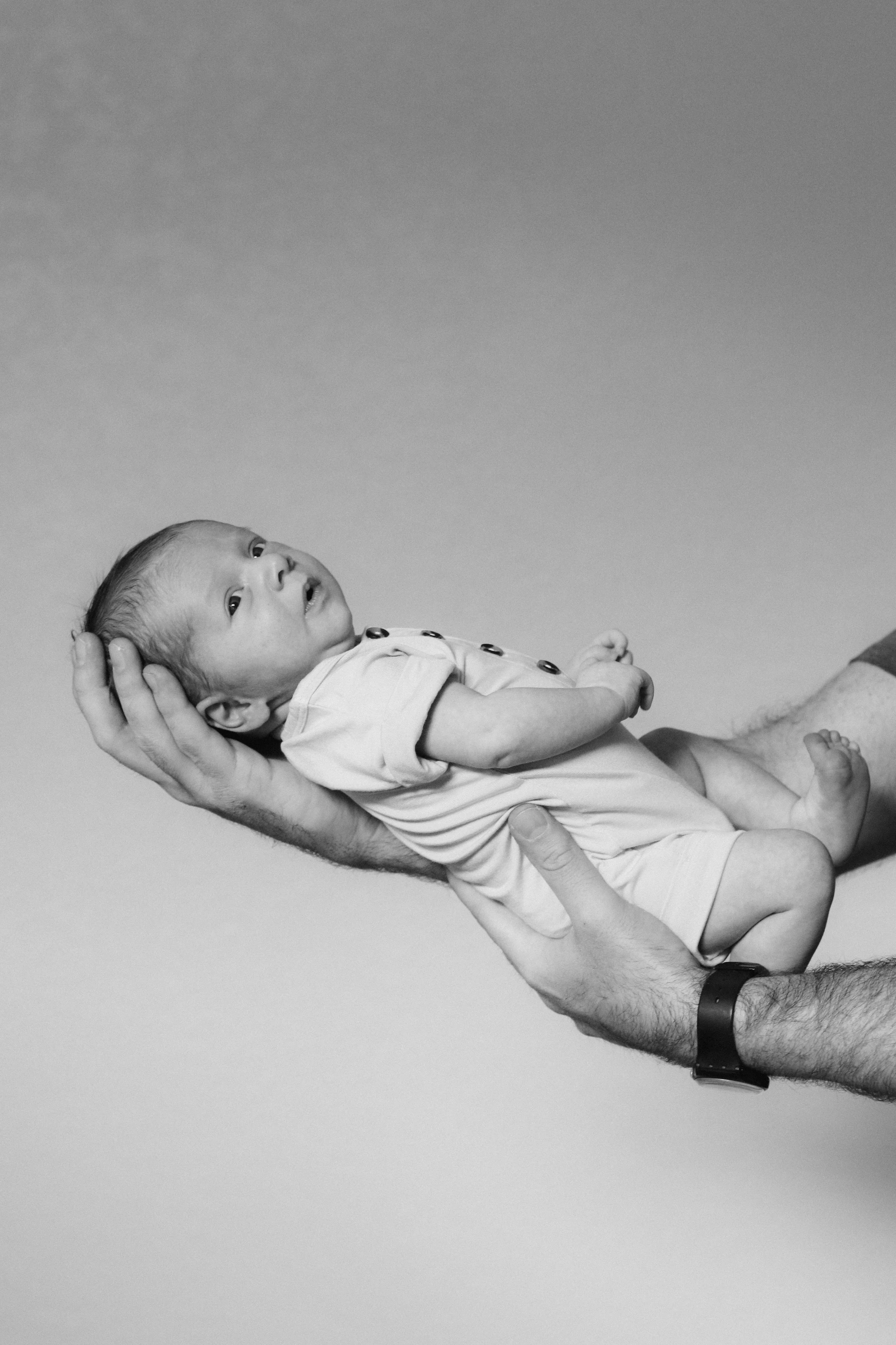 black and white photo of infant in mans hands