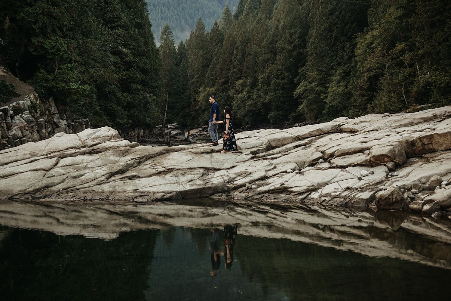 Copy of couple walking on rock reflection in water by trees