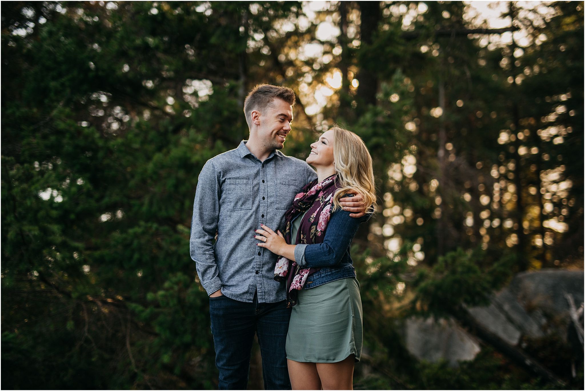 guy arm around girl looking at each other sunny engagement session