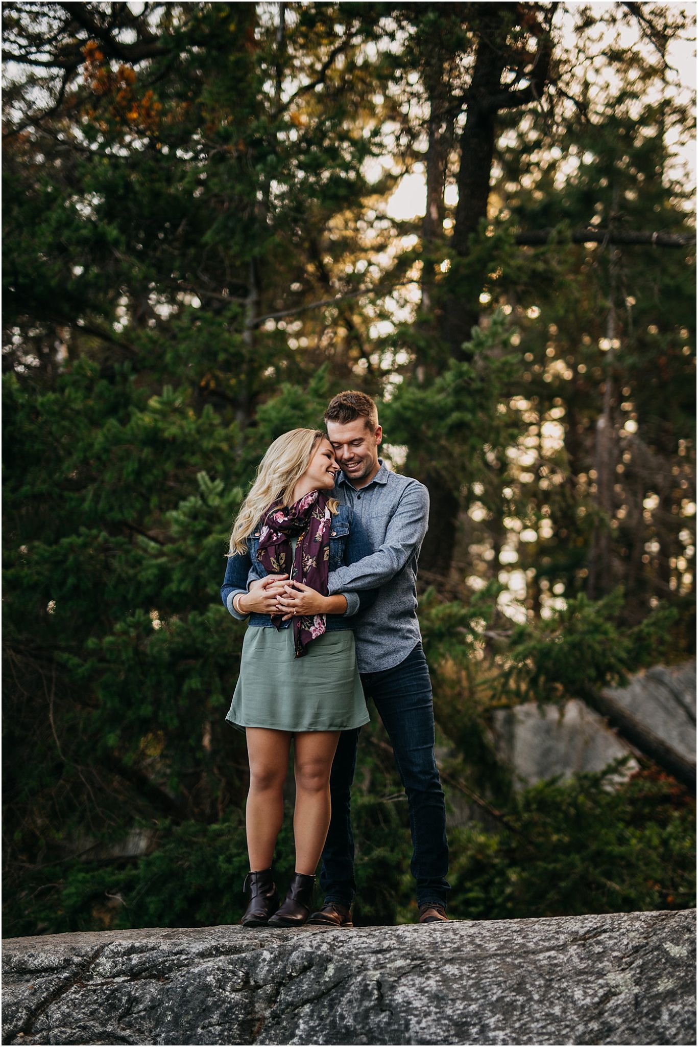 couple standing on rock in forest 