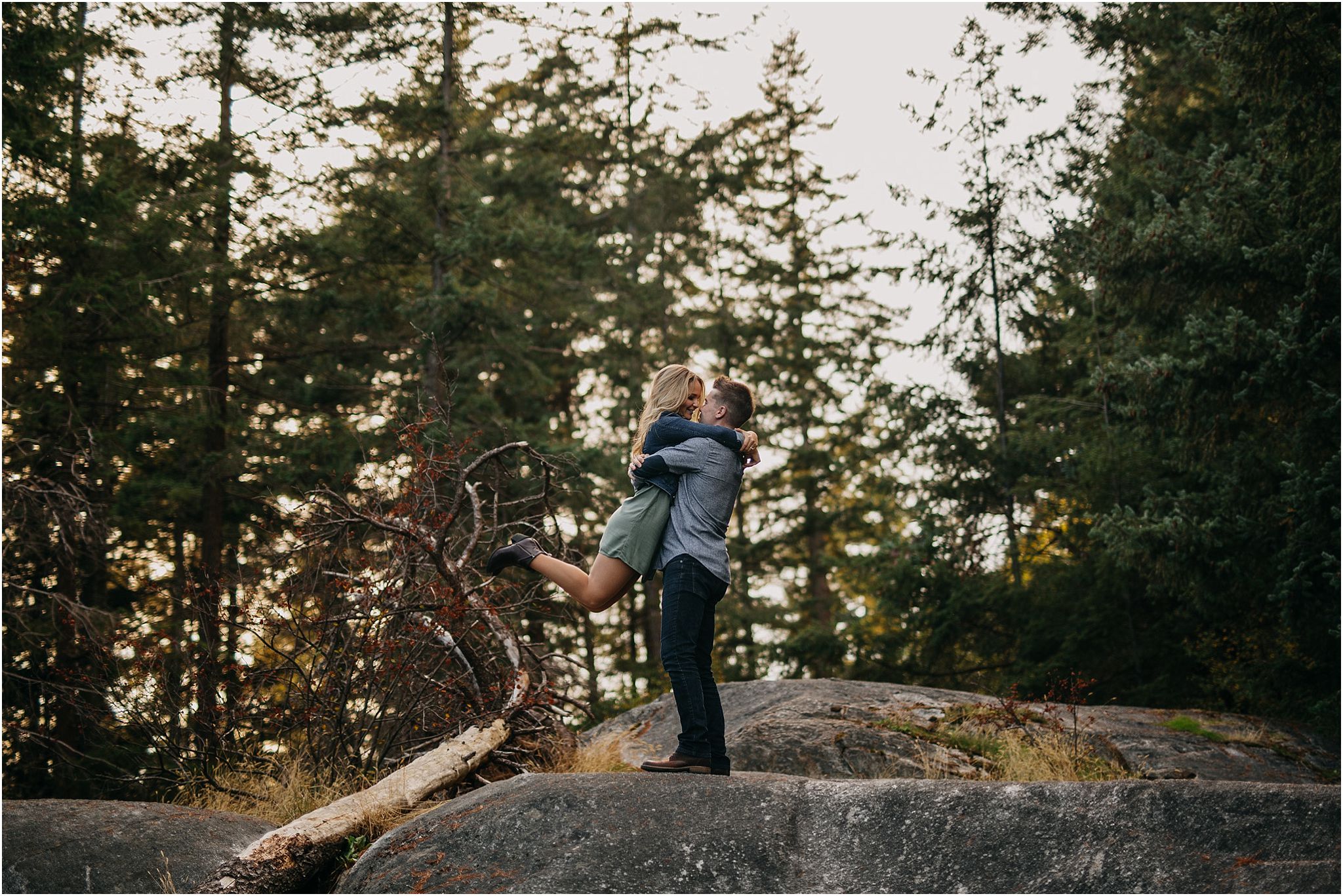 guy picking up girl kissing sunshine in forest