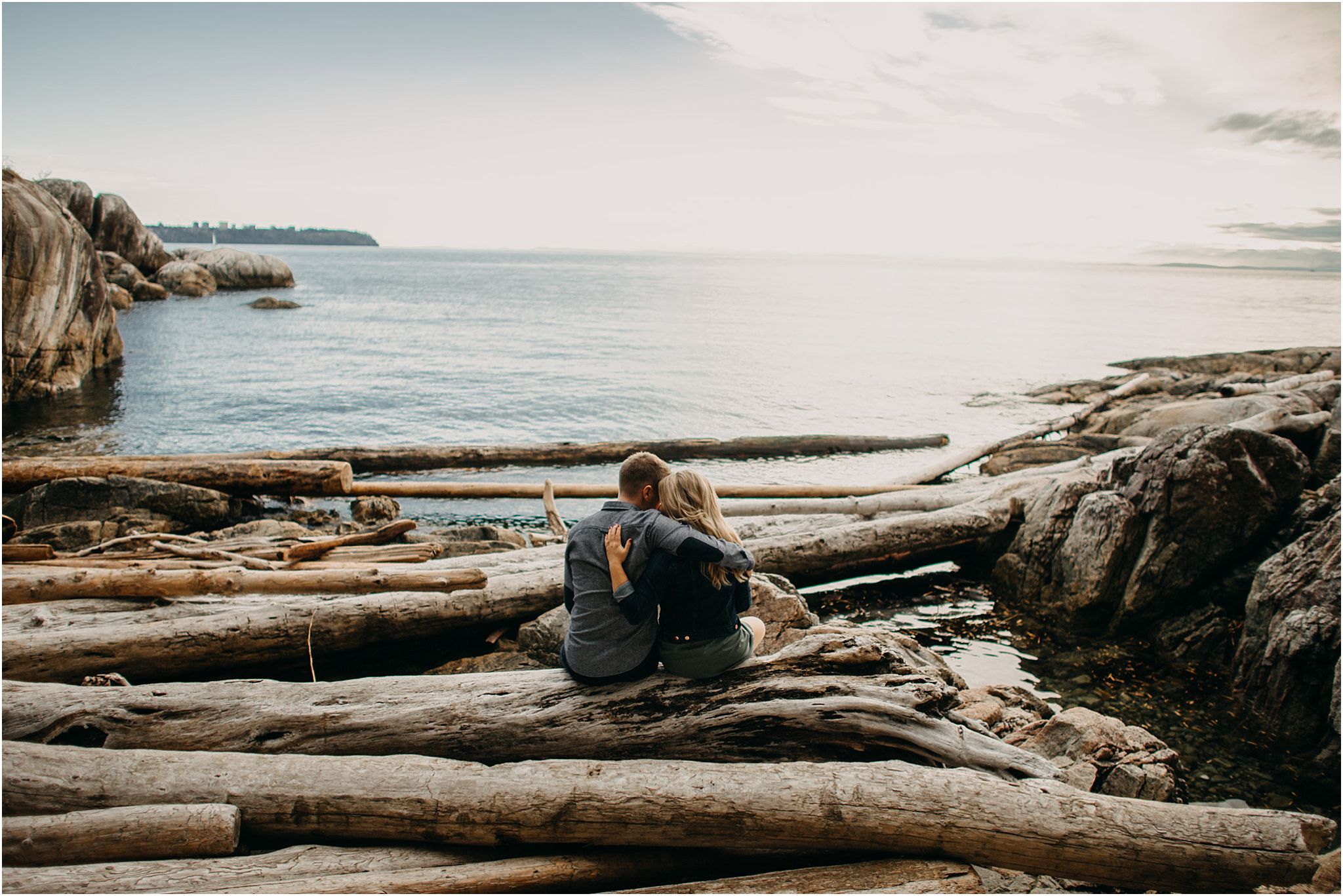 couple sitting on log lighthouse park ocean
