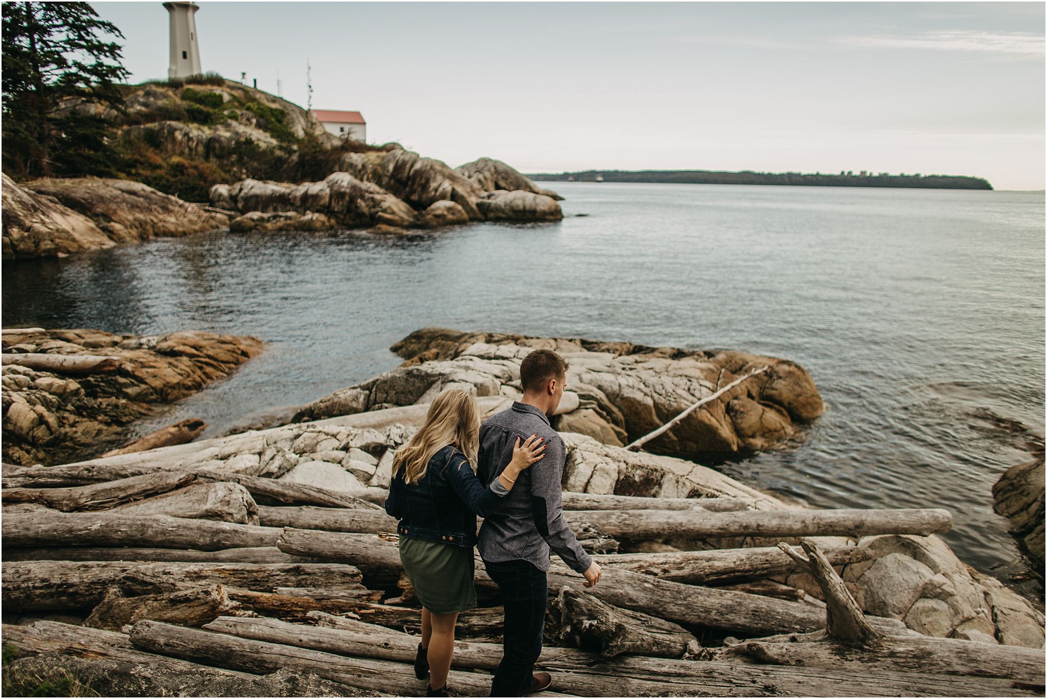 couple walking on logs at beach lighthouse park