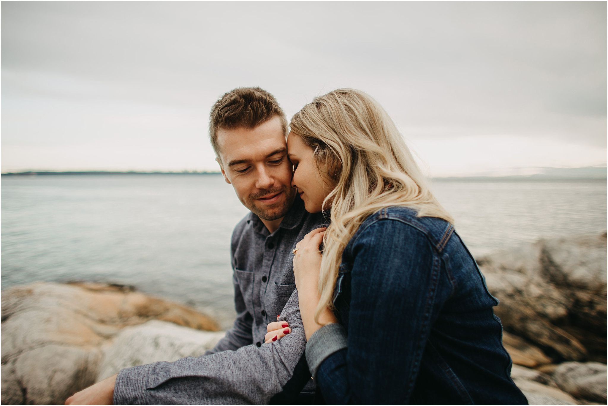 couple snuggling by ocean engagement session
