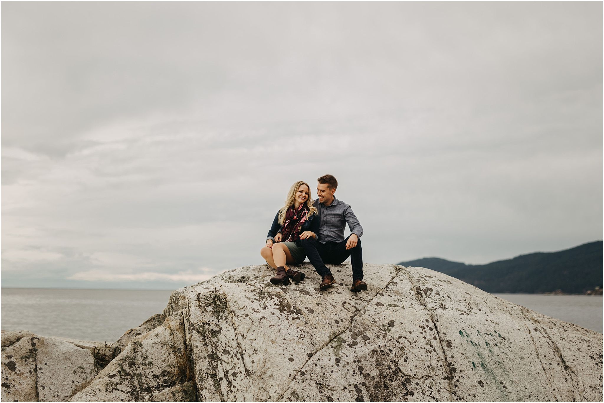 couple sitting on rock by ocean at lighthouse park
