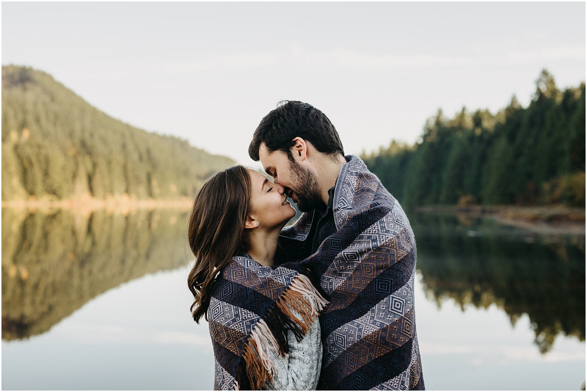 couple wrapped in blanket lake reflection rolley lake engagement