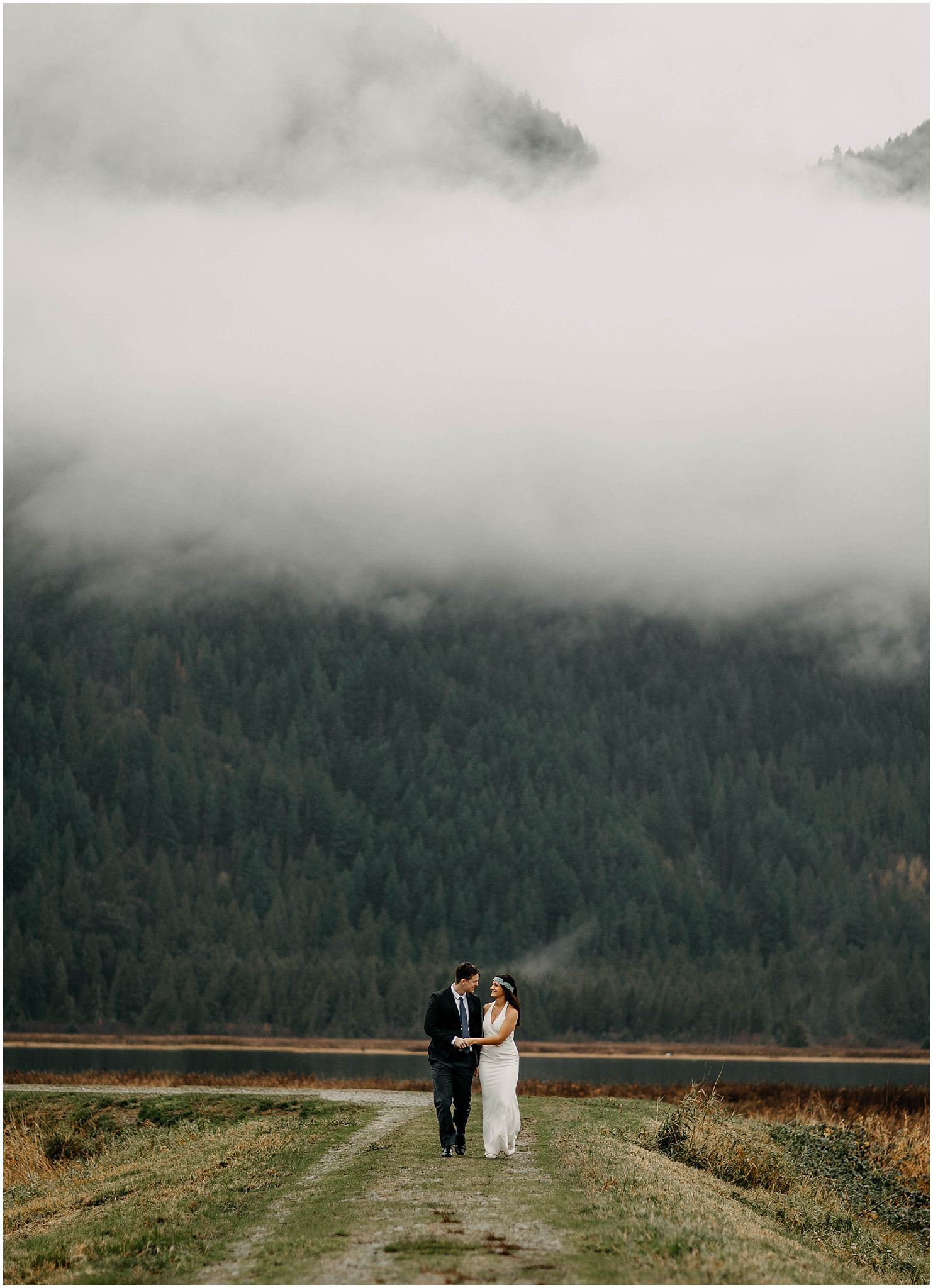 couple walking along pitt lake marsh cloud fog mountains engagement