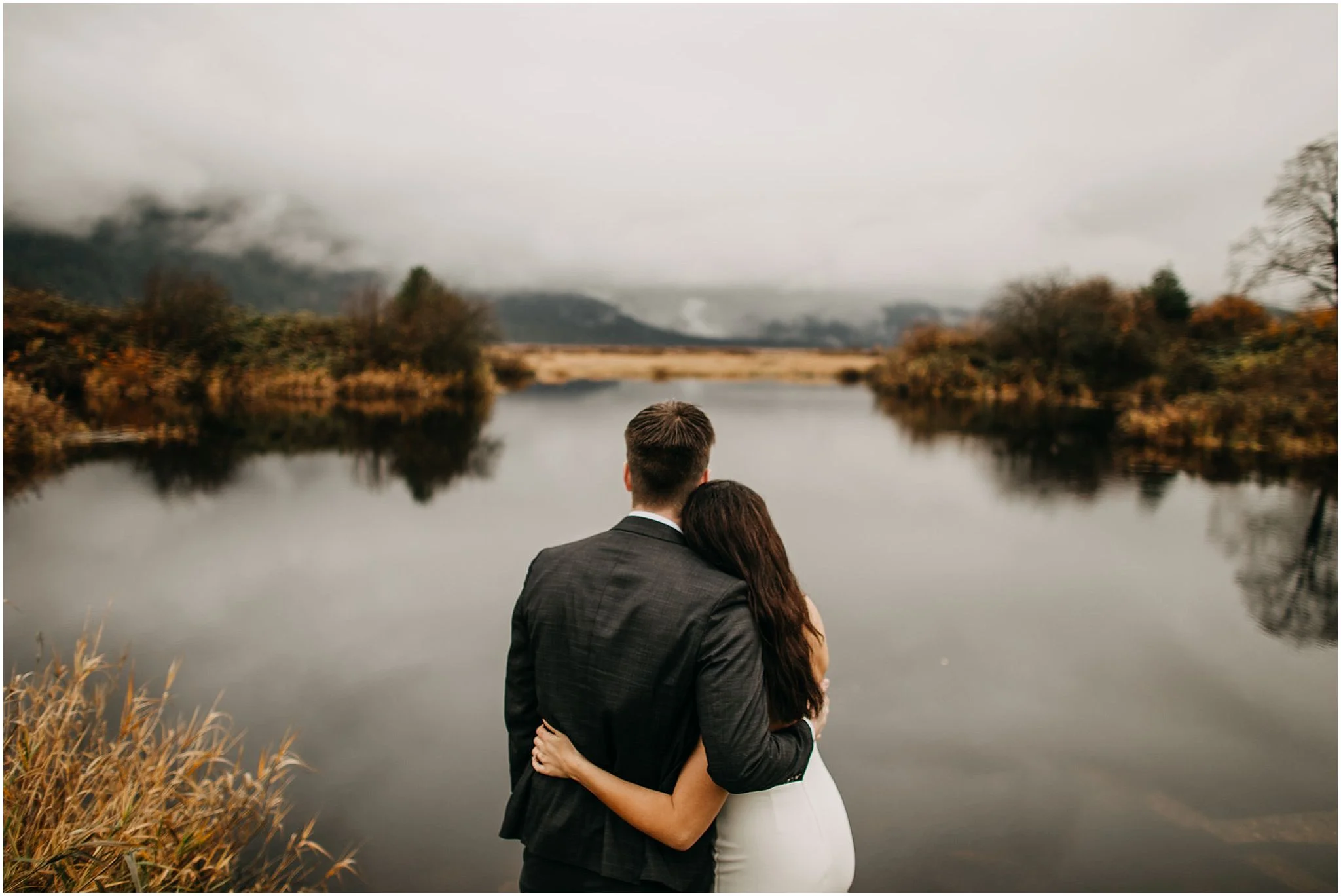 couple arms wrapped around each other looking out at foggy view pitt lake