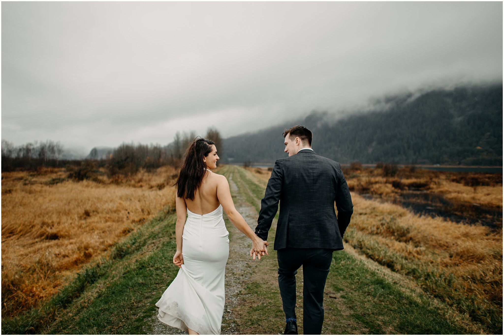 couple holding hands walking along pitt lake marsh engagement photos