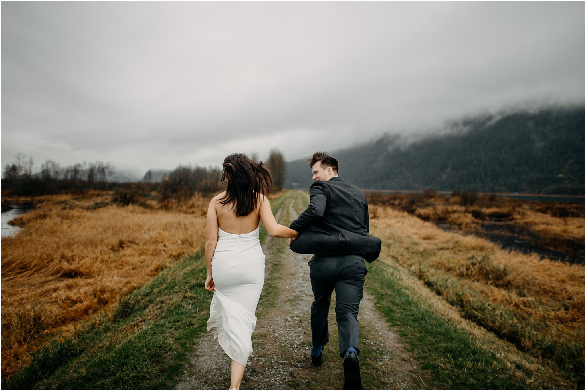 couple holding hands running away on pitt lake marsh