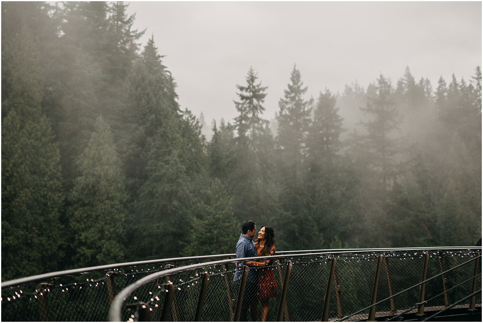 engaged couple on cliffwalk capilano suspension bridge fog rain trees 
