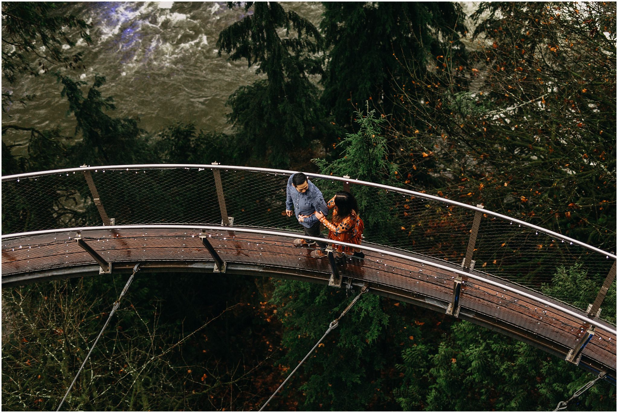 engaged couple holding hands walking on cliffwalk capilano suspension bridge 