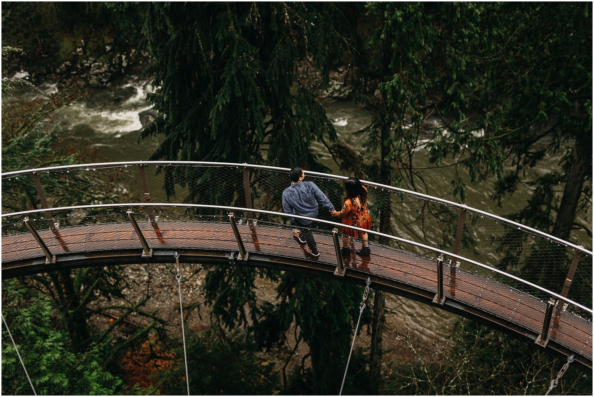 engaged couple holding hands walking along cliffwalk capilano suspension bridge