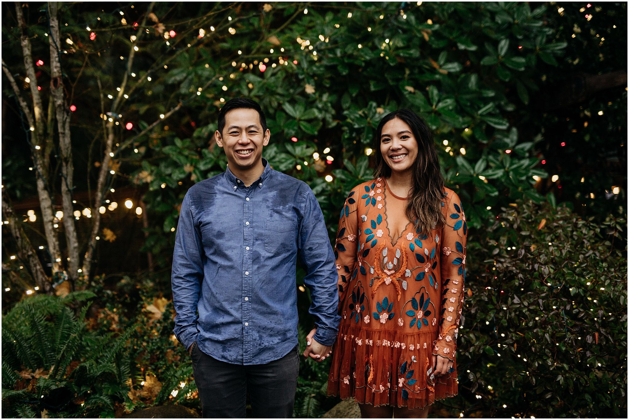 couple engagement standing in capilano suspension bridge canyon lights
