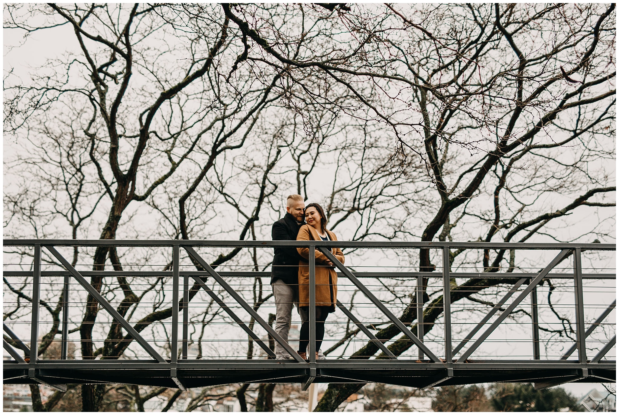 couple on bridge on granville island winter trees engagement