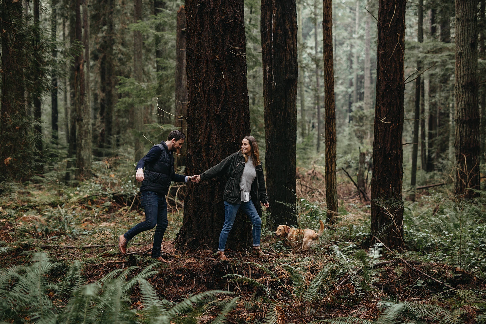 couple walking on log in forest pacific spirit park engagement