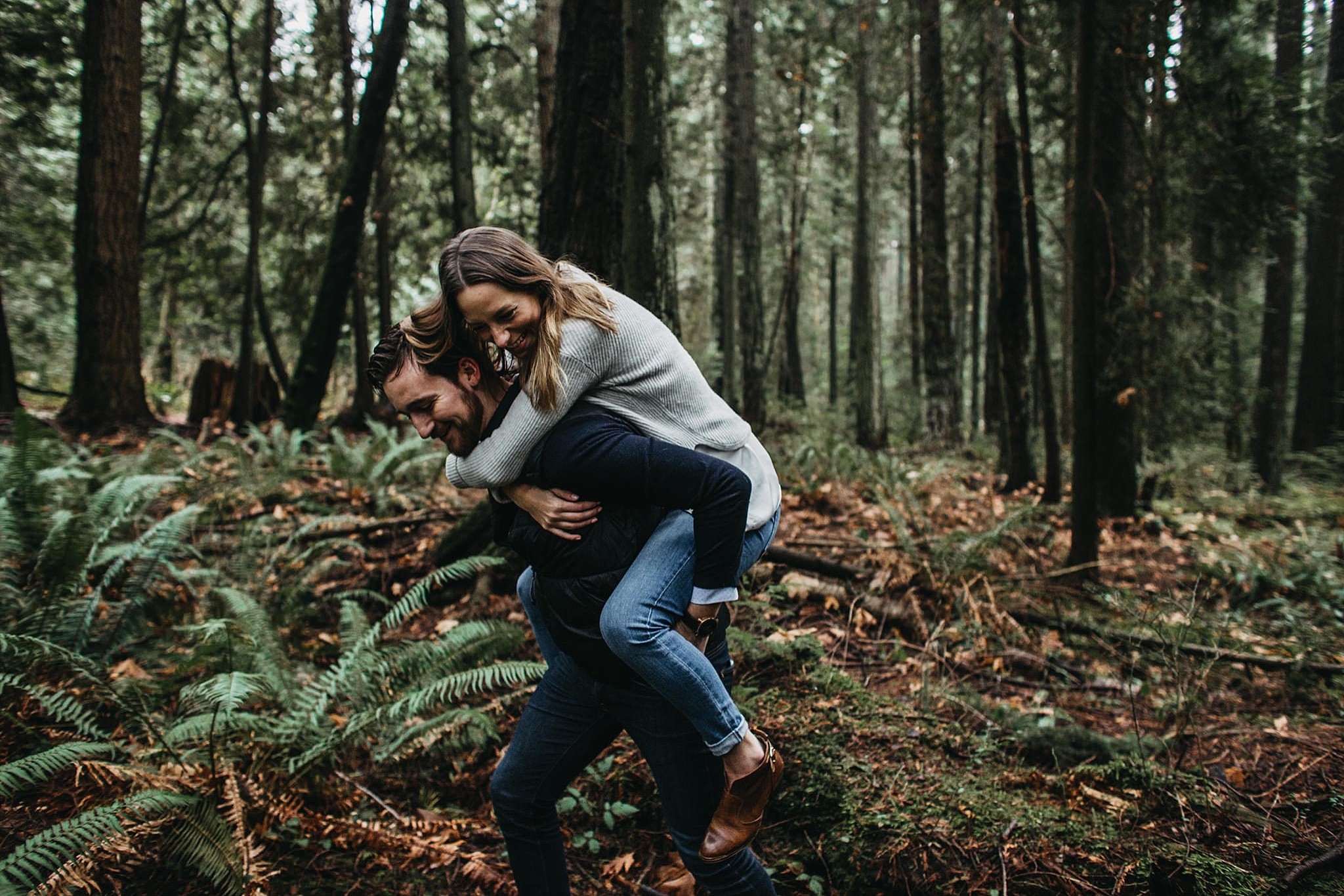 couple piggyback in forest of pacific spirit park