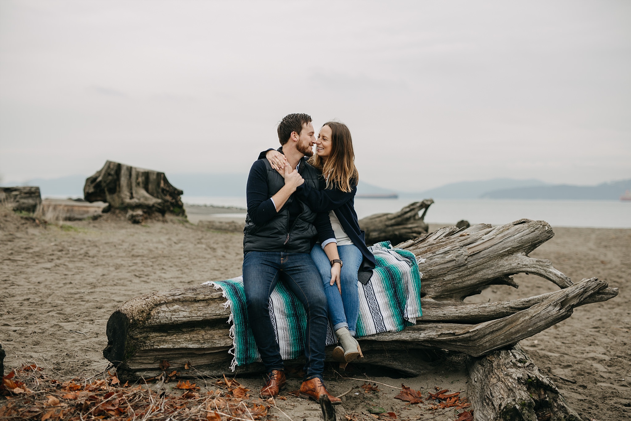 couple sitting on blanket on log spanish banks engagement