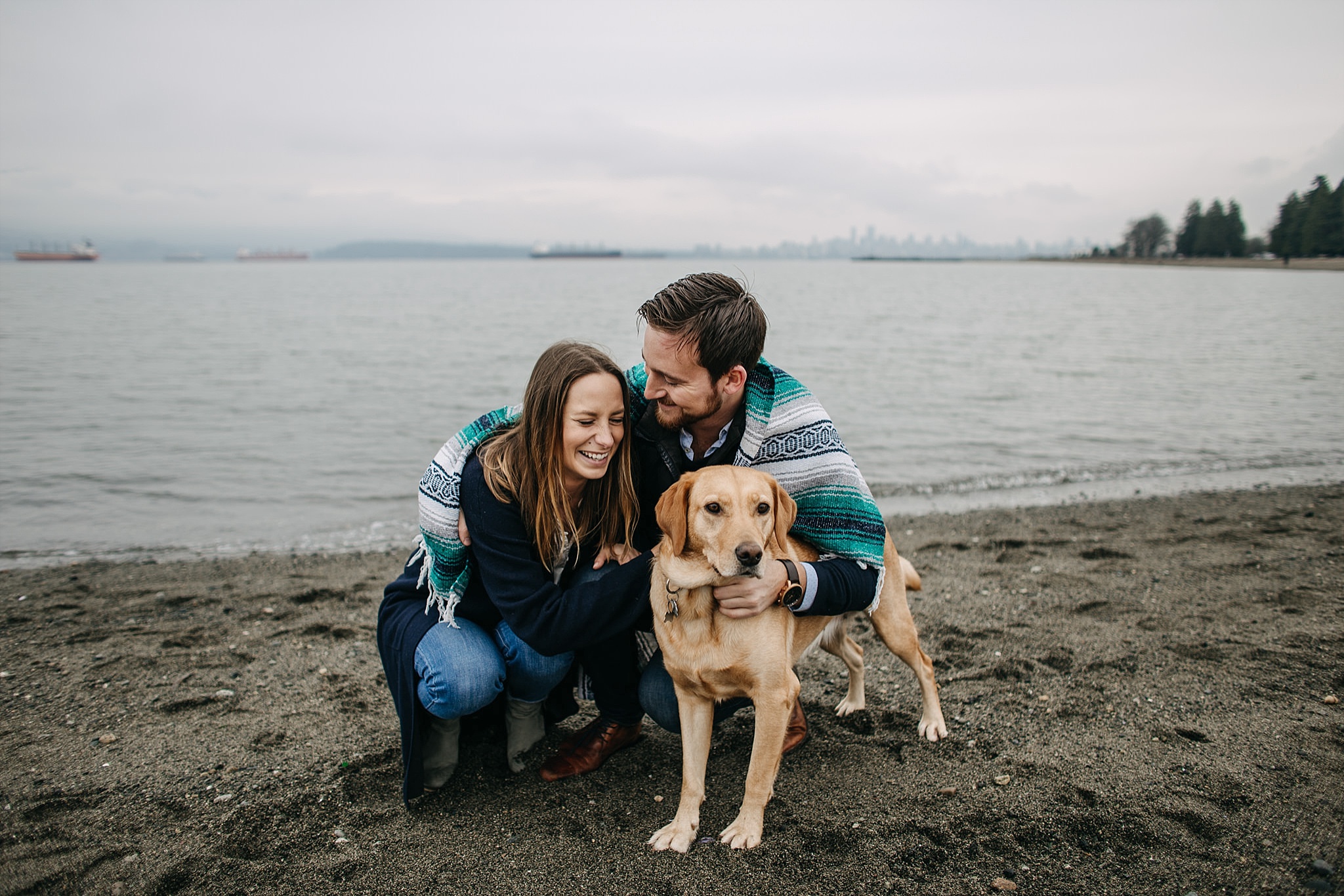 couple with dog family photo wrapped in blanket on spanish banks beach