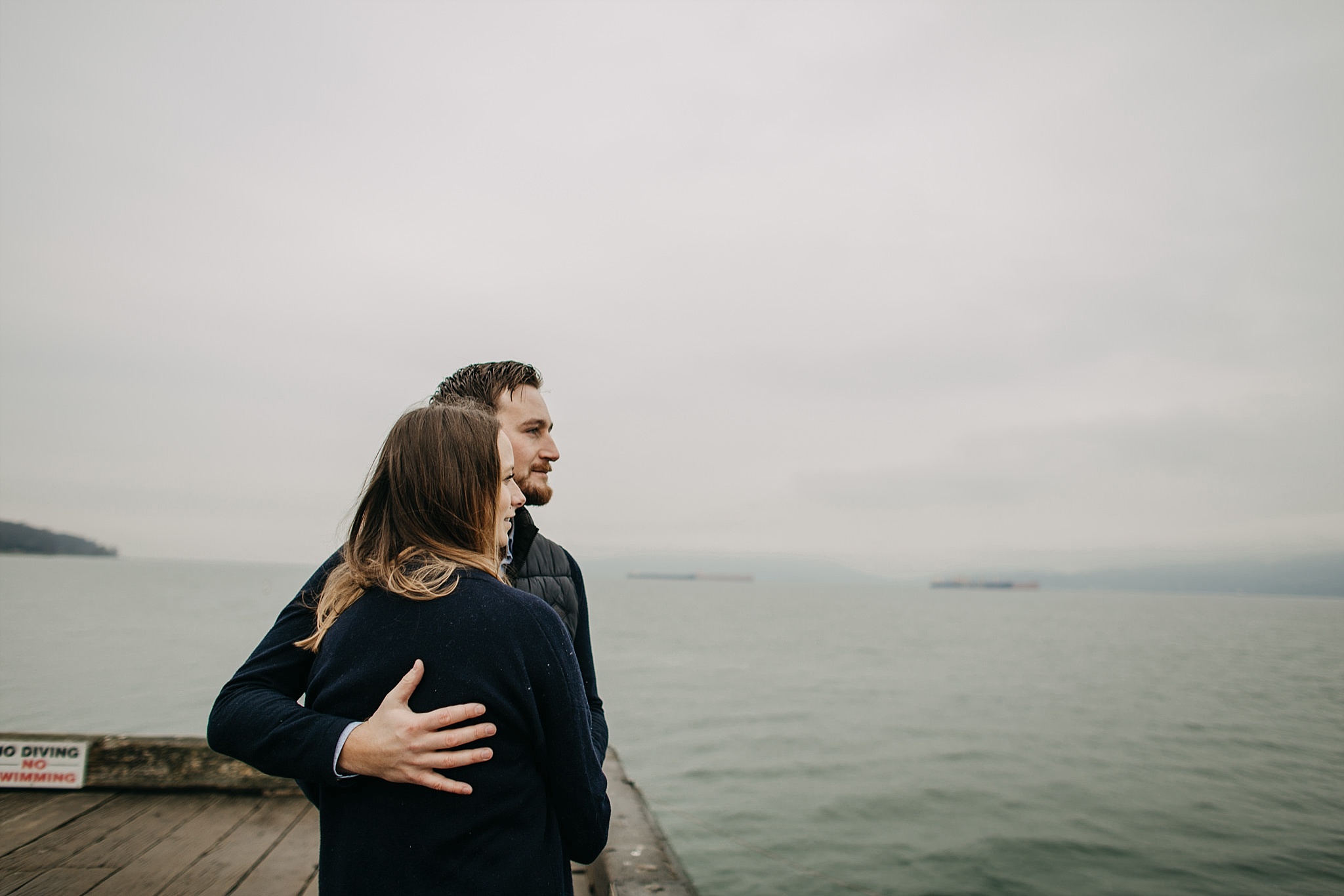 couple on dock looking out at ocean spanish banks engagement photos