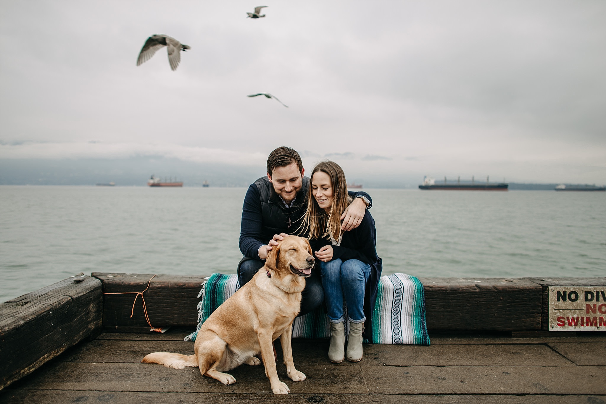 couple with puppy on dock birds flying spanish banks engagement
