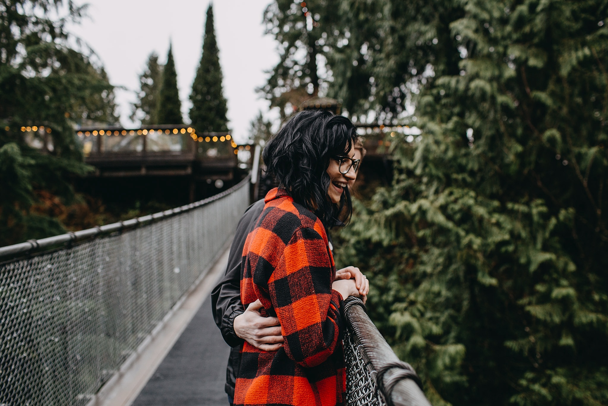 couple looking over capilano suspension bridge engagement