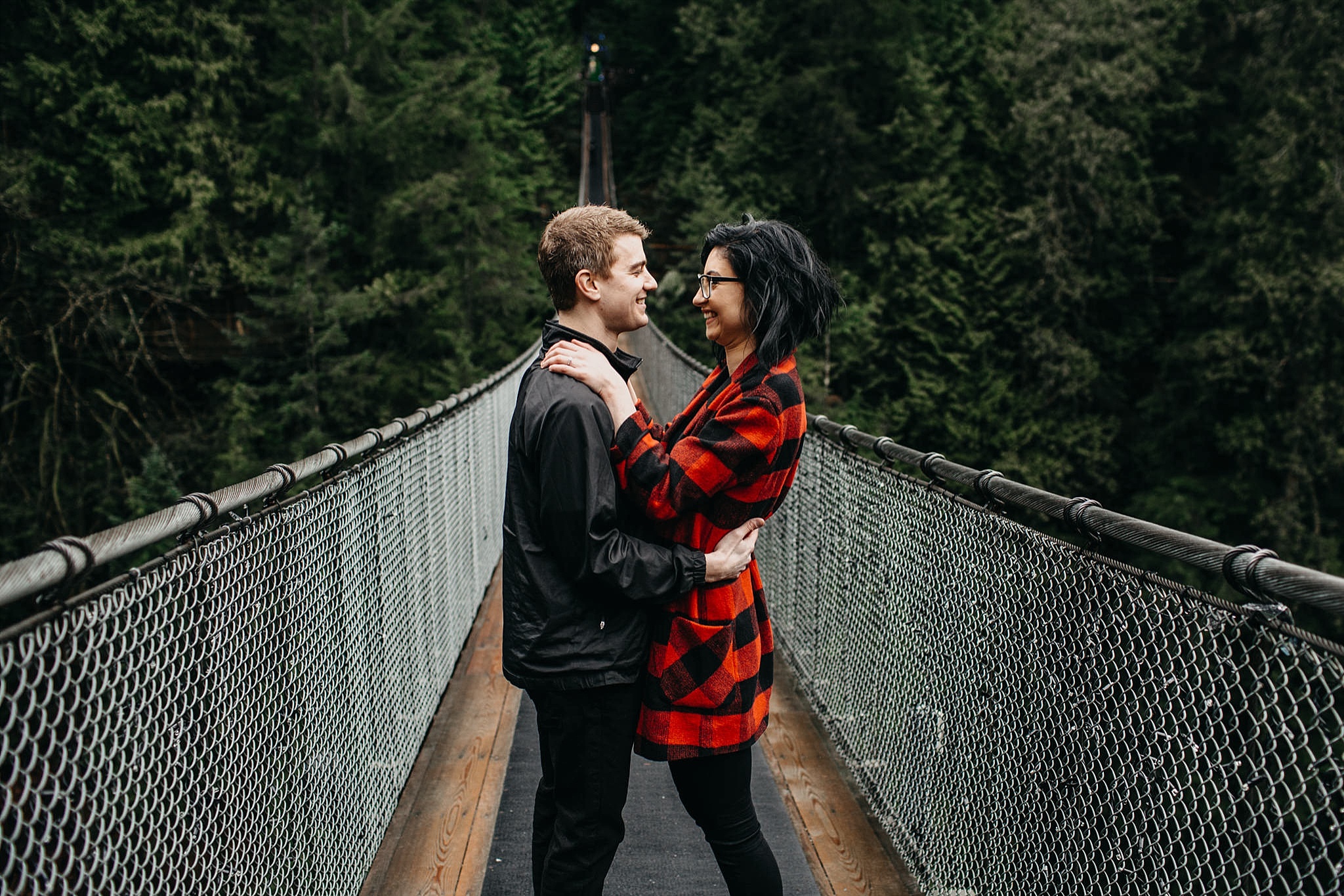 couple hug on capilano suspension bridge engagement photos rain pnw