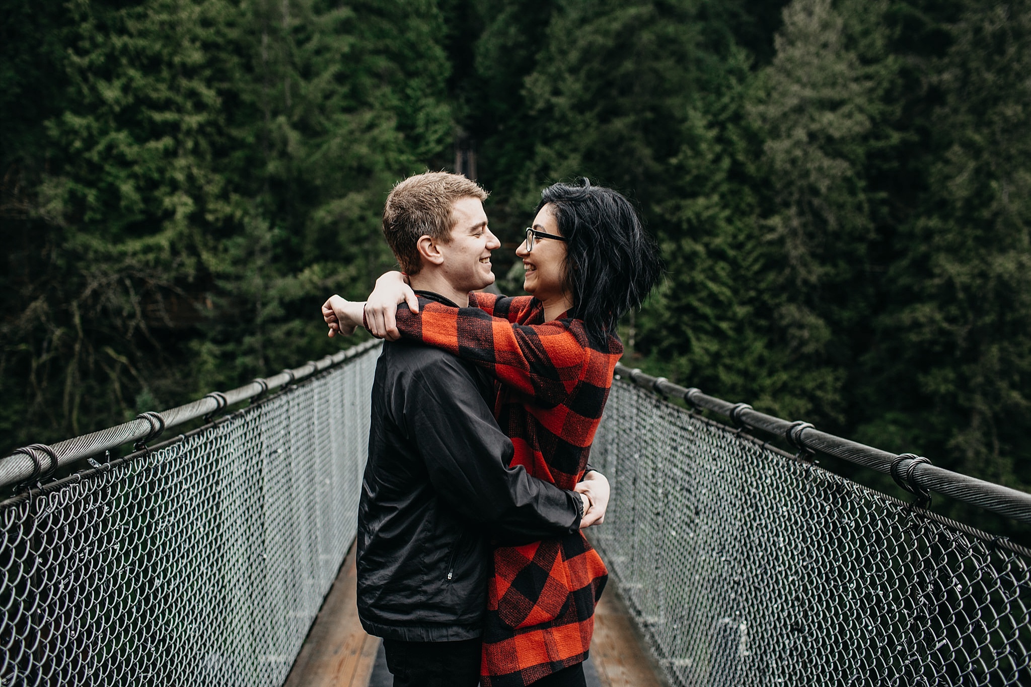 couple hugging on capilano suspension bridge north vancouver engagement session