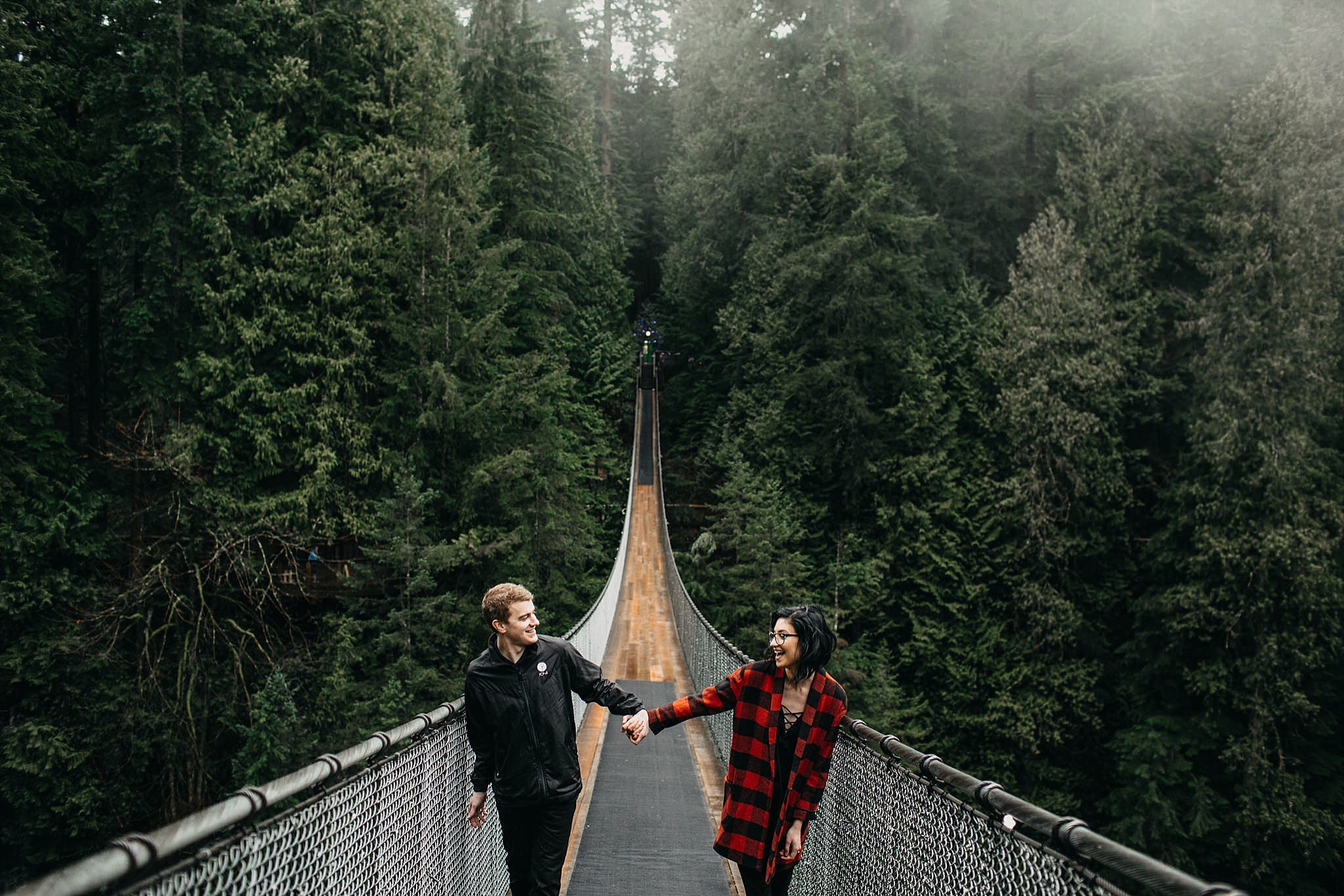 couple holding hands walking on capilano suspension bridge