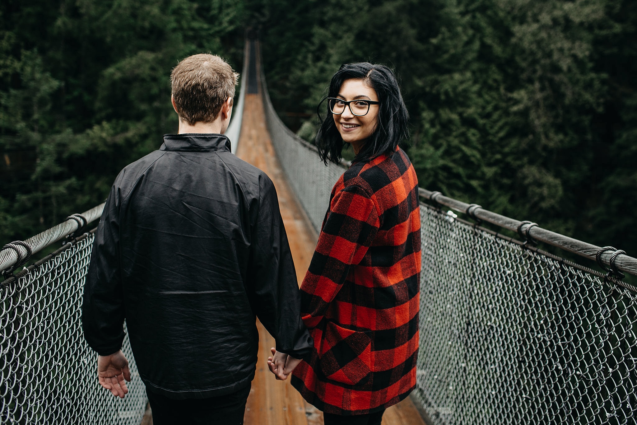 couple walking across capilano suspension bridge engagement photos