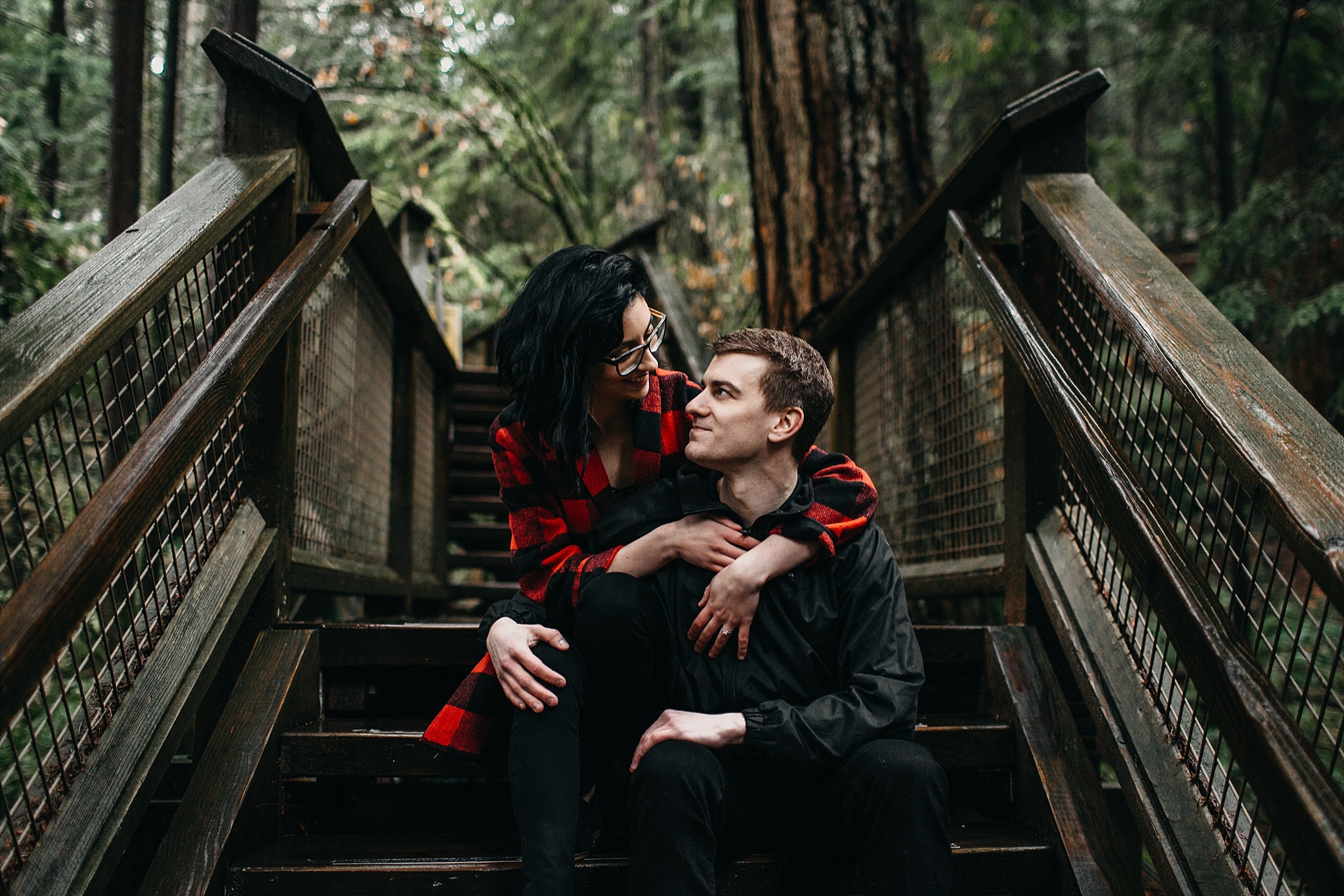 couple sitting on steps looking at each other engagement photos capilano suspension bridge