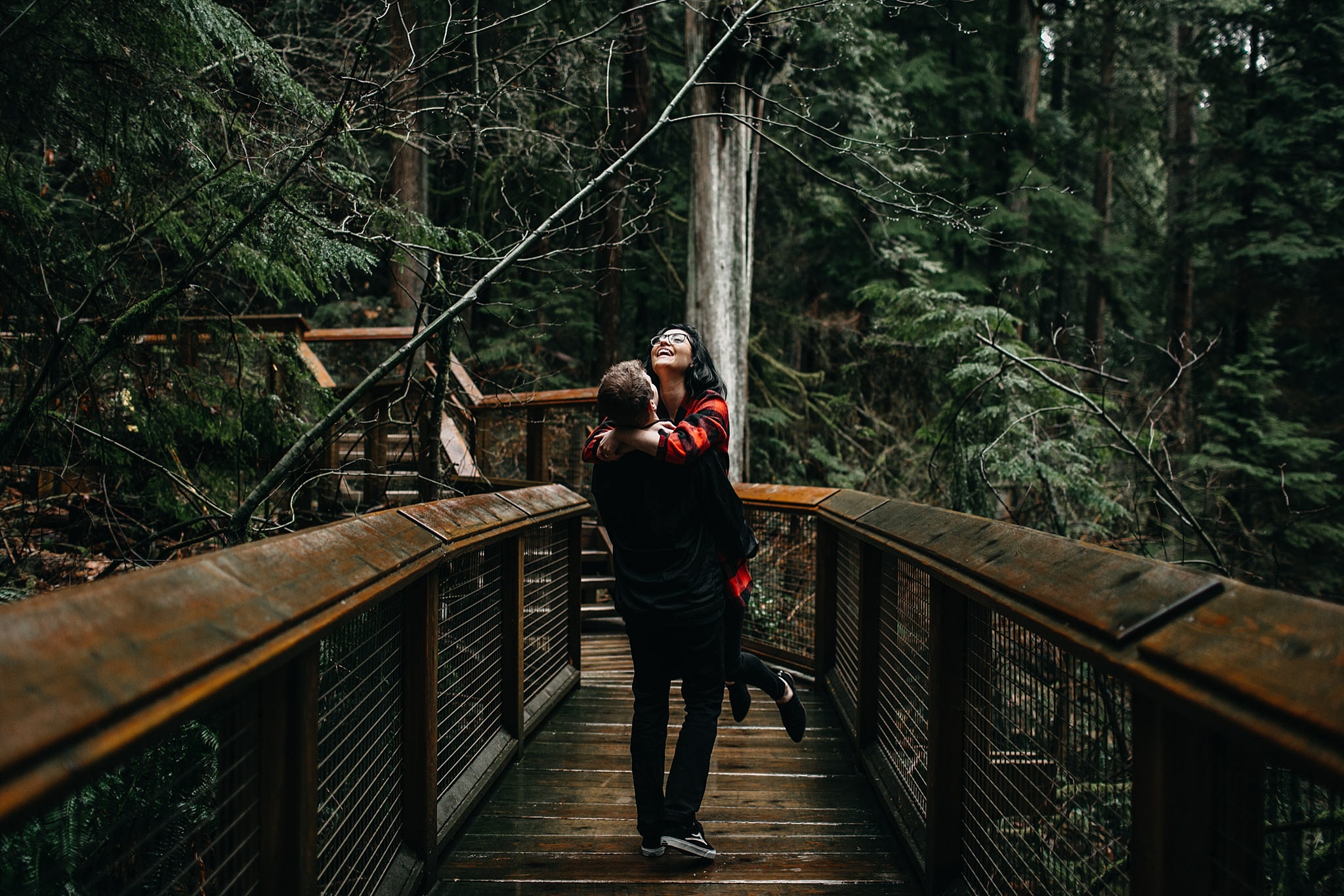 couple guy lifting girl off ground capilano suspension bridge engagement photos