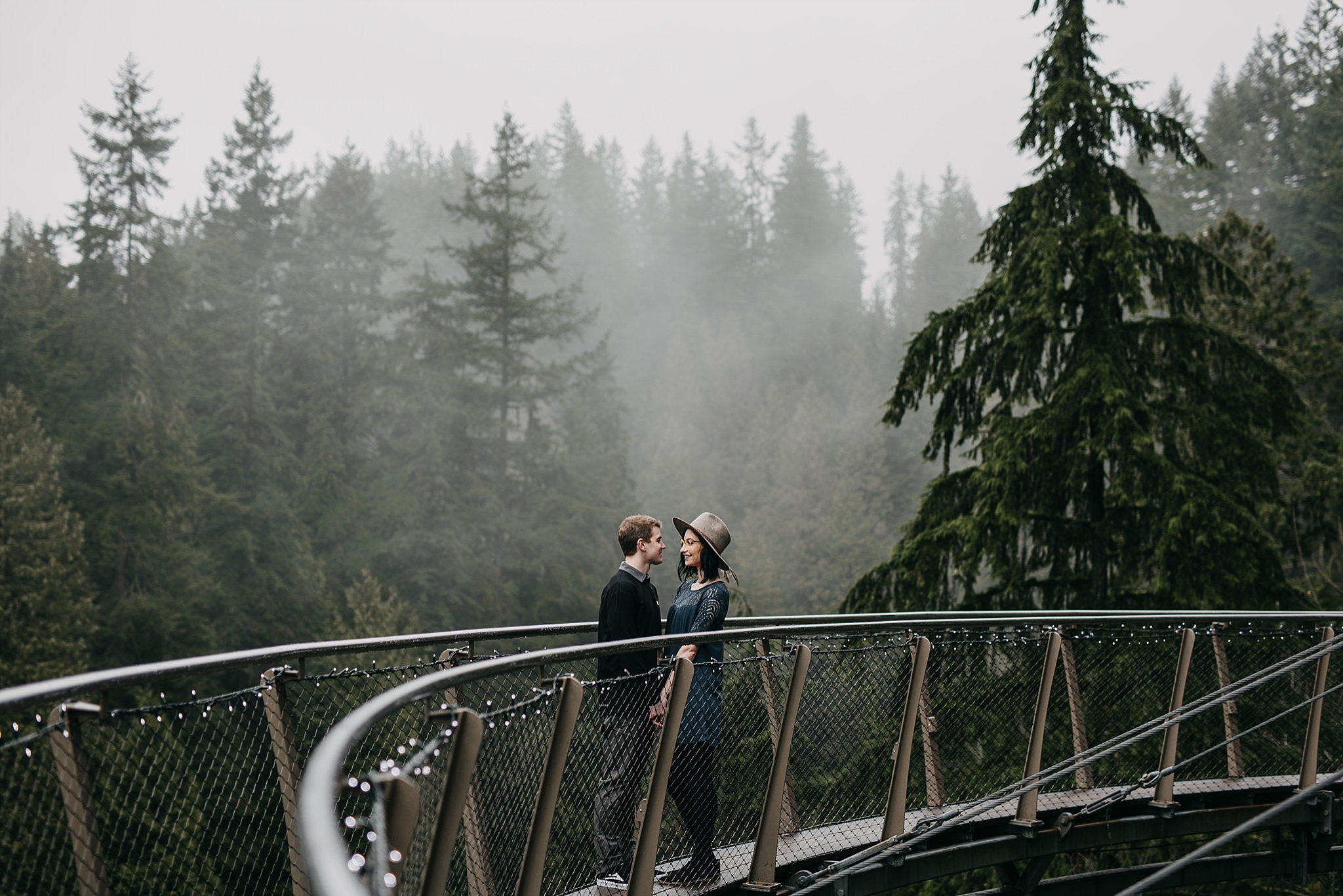 couple standing on cliff walk capilano suspension bridge foggy forest