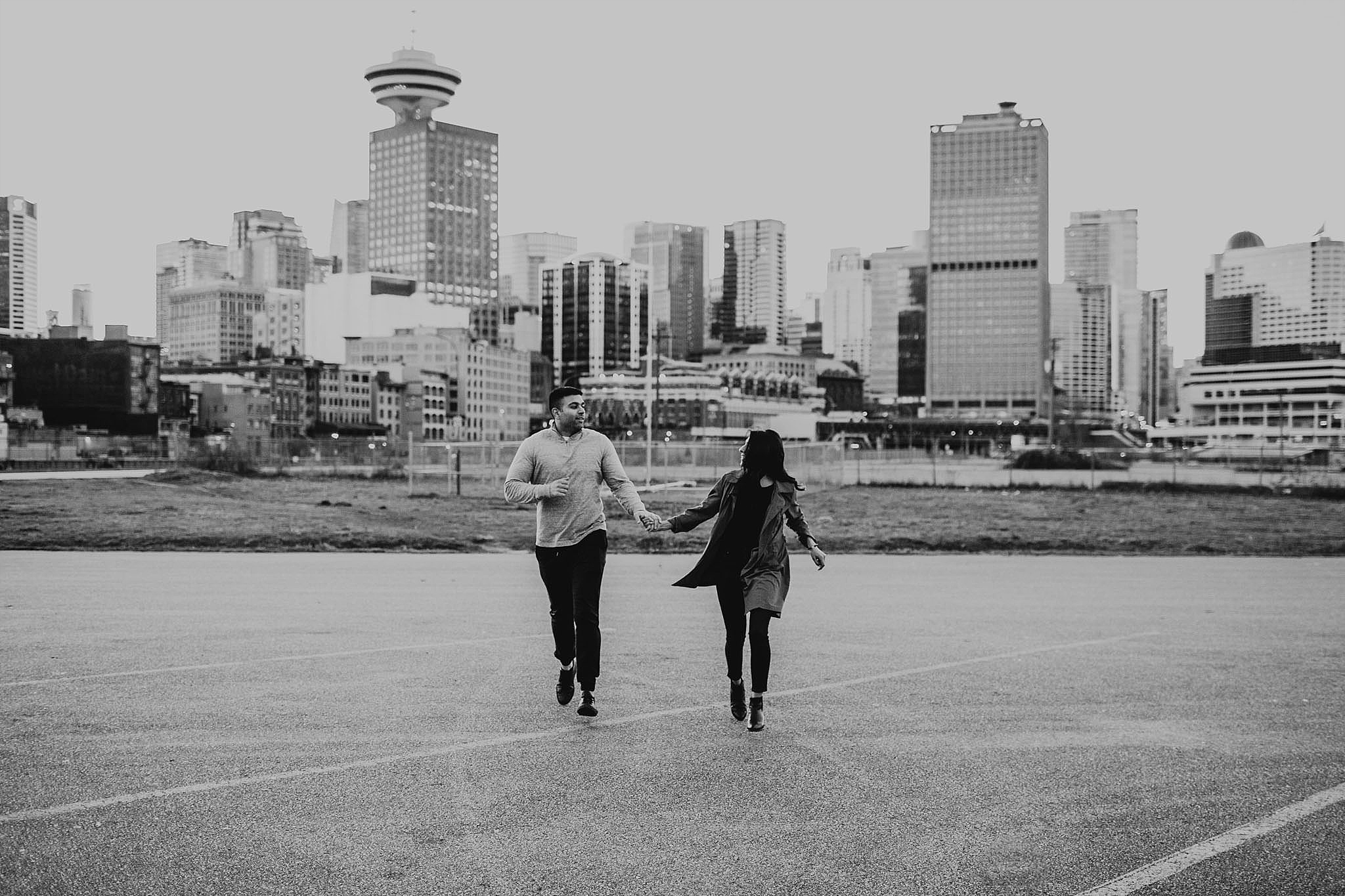 couple running city skyline behind downtown vancouver