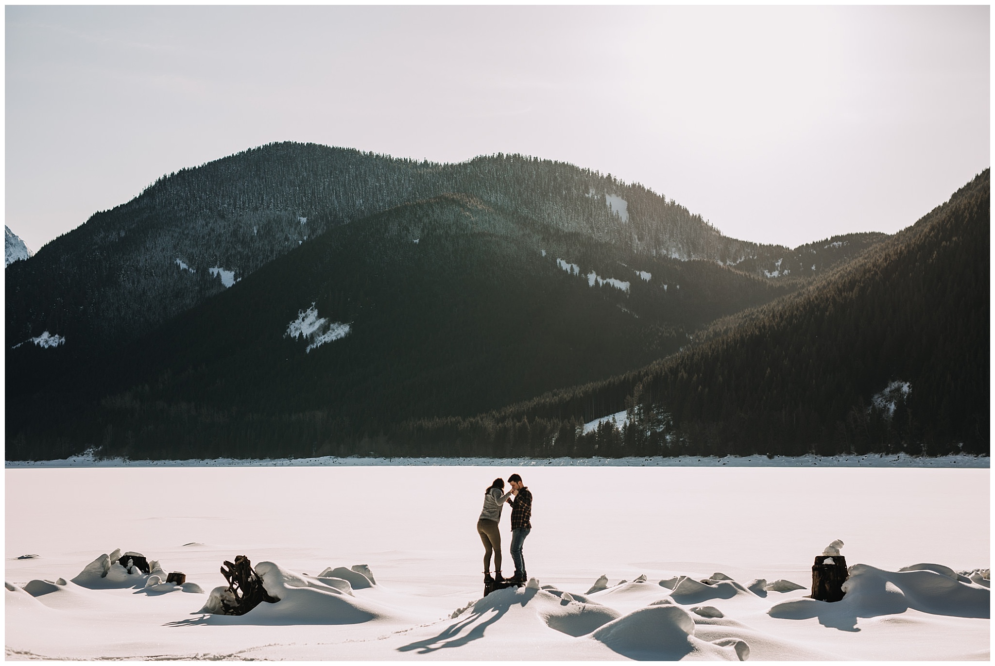 couple on tree stump at jones lake snow mountains sun