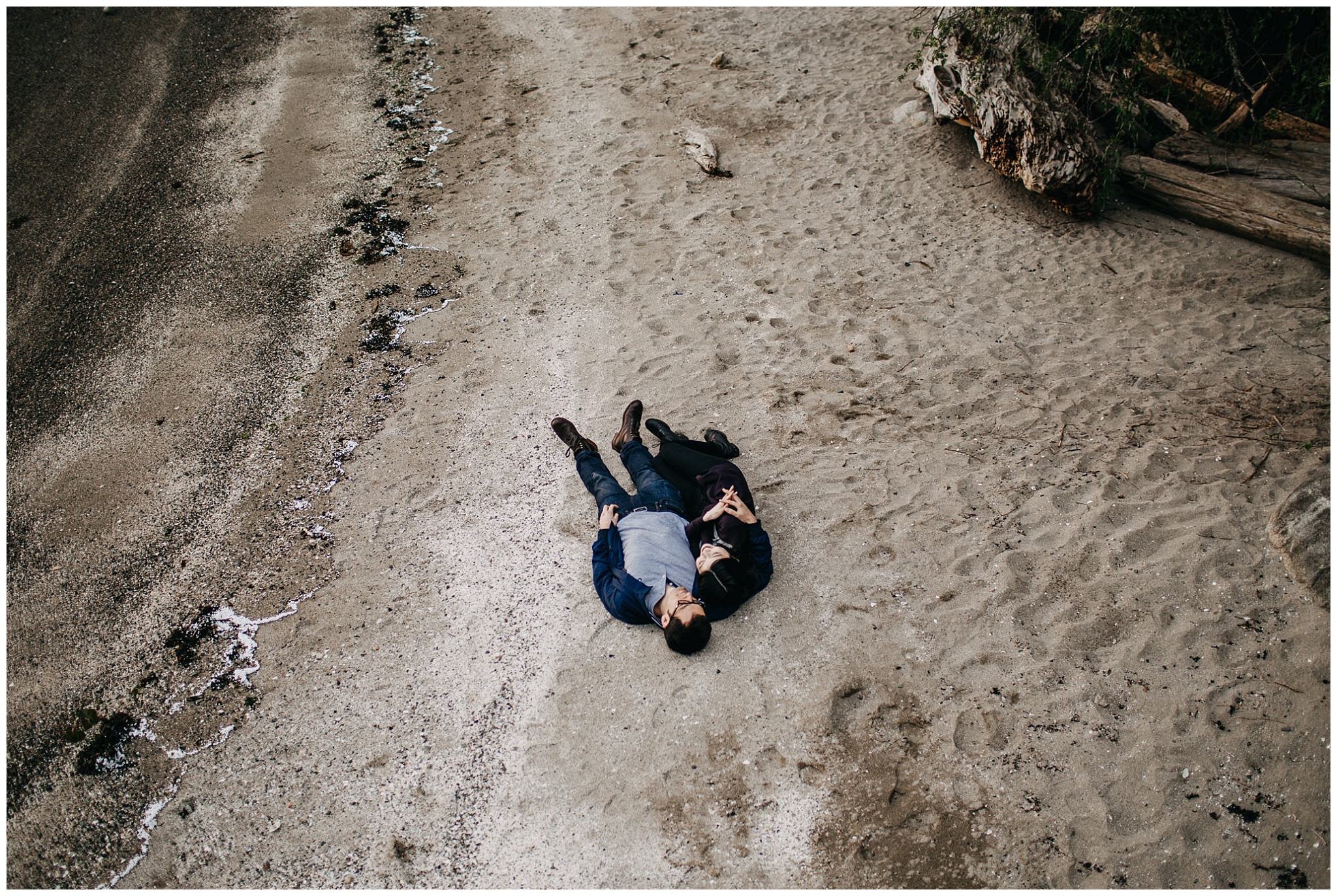 couple laying down on beach aerial shot engagement photos north vancouver