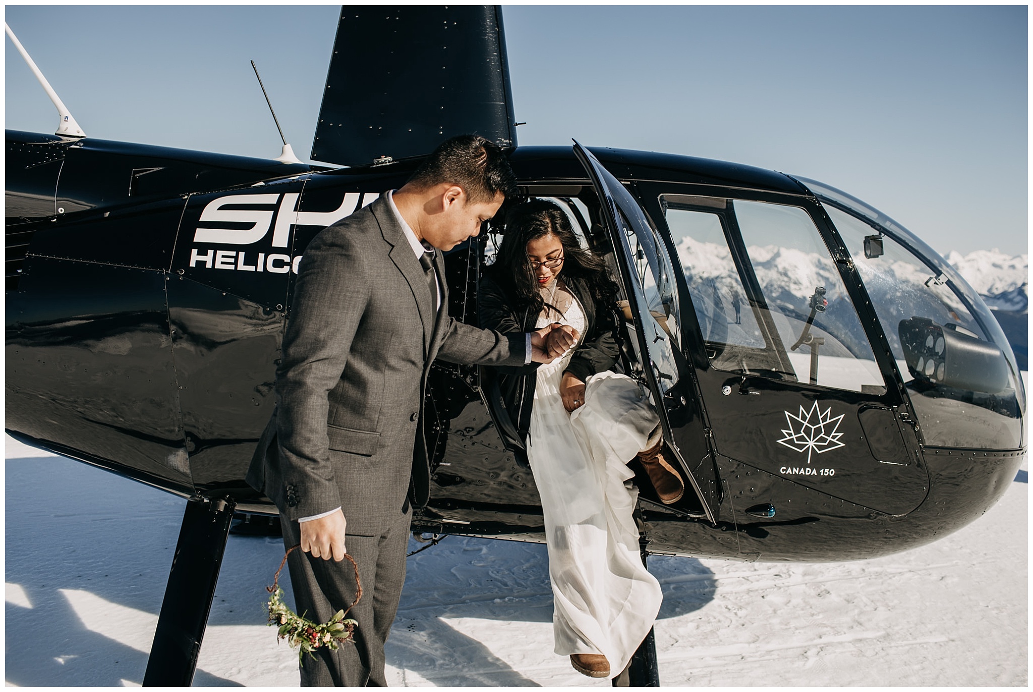 groom helping bride out of helicopter sky helicopters snowy mountaintop wedding portraits