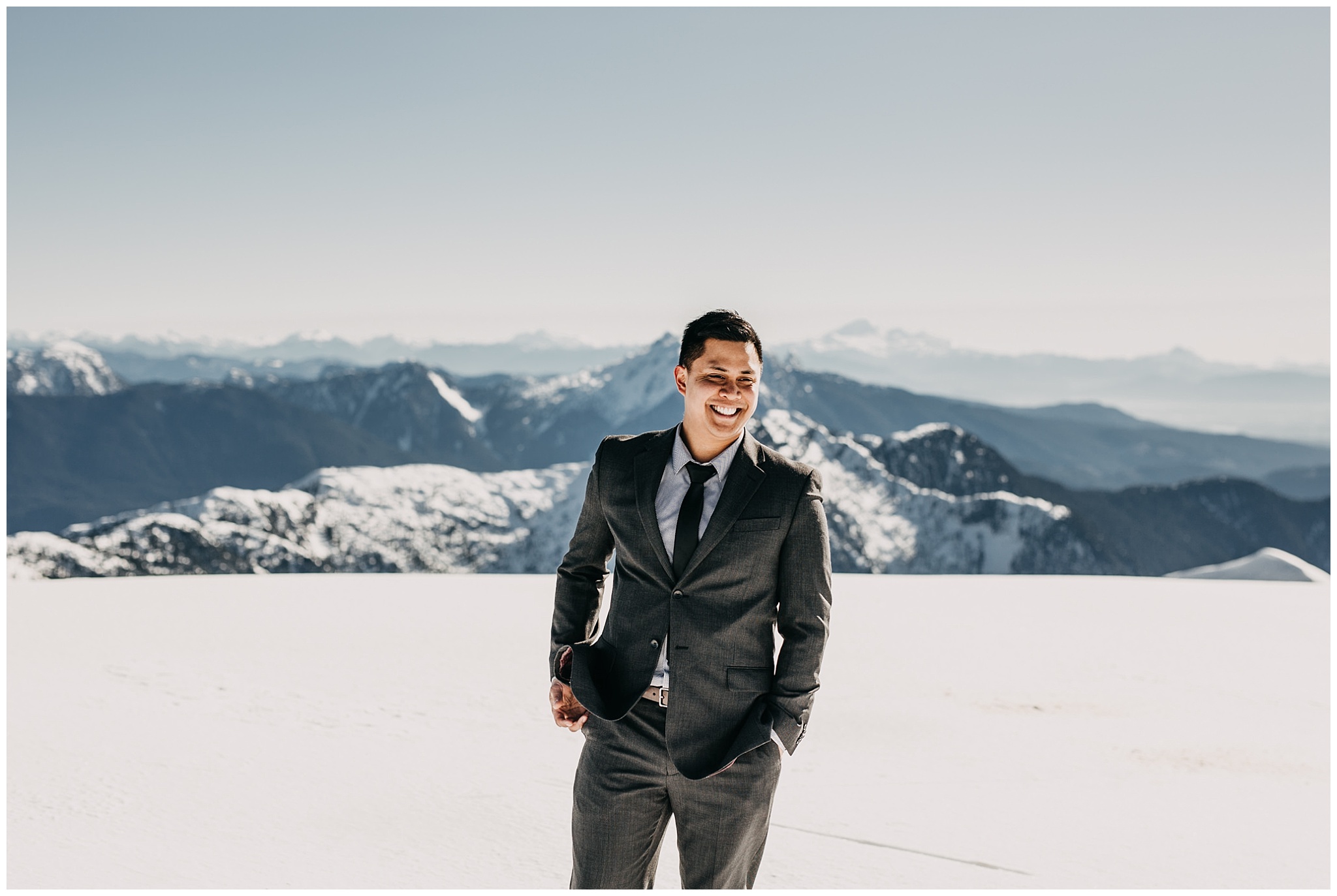 groom portrait suit mountaintop snow sun sky helicopters wedding